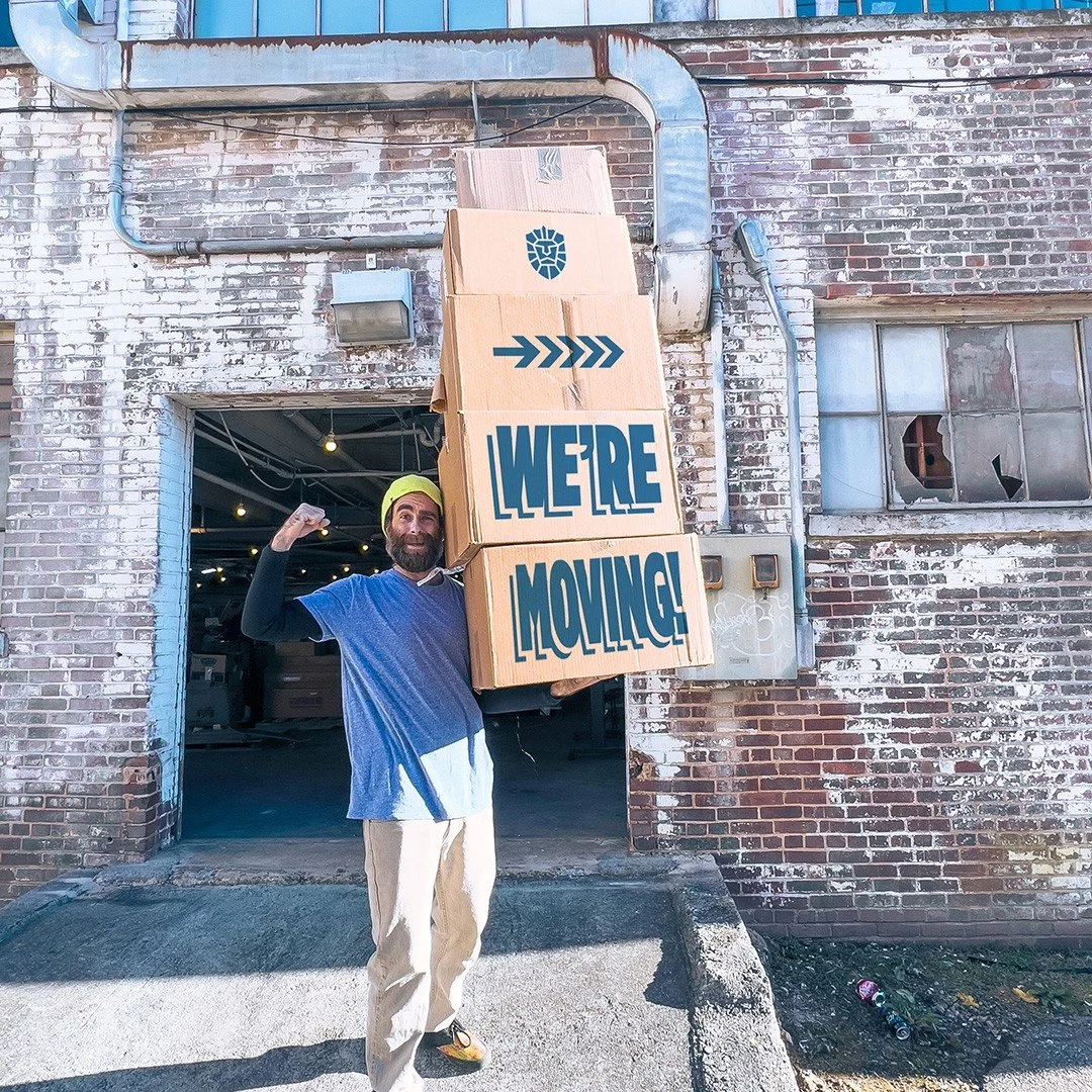Ashley holding boxes in front of the print shop that say "We're moving!'