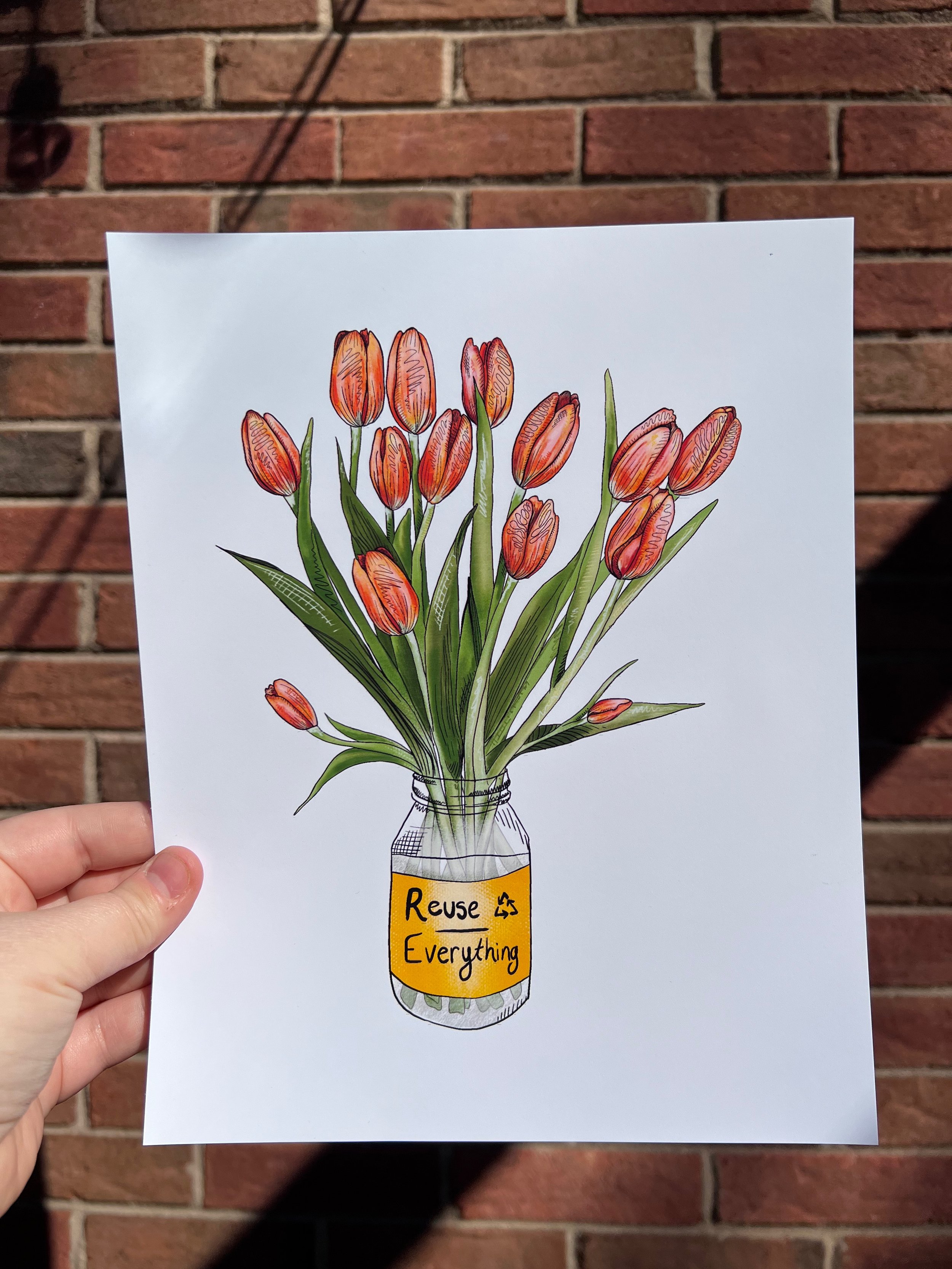 A drawing of a glass jar with a yellow label reading 'Reuse Everything' holding a bouquet of orange tulips, held against a brick wall background.