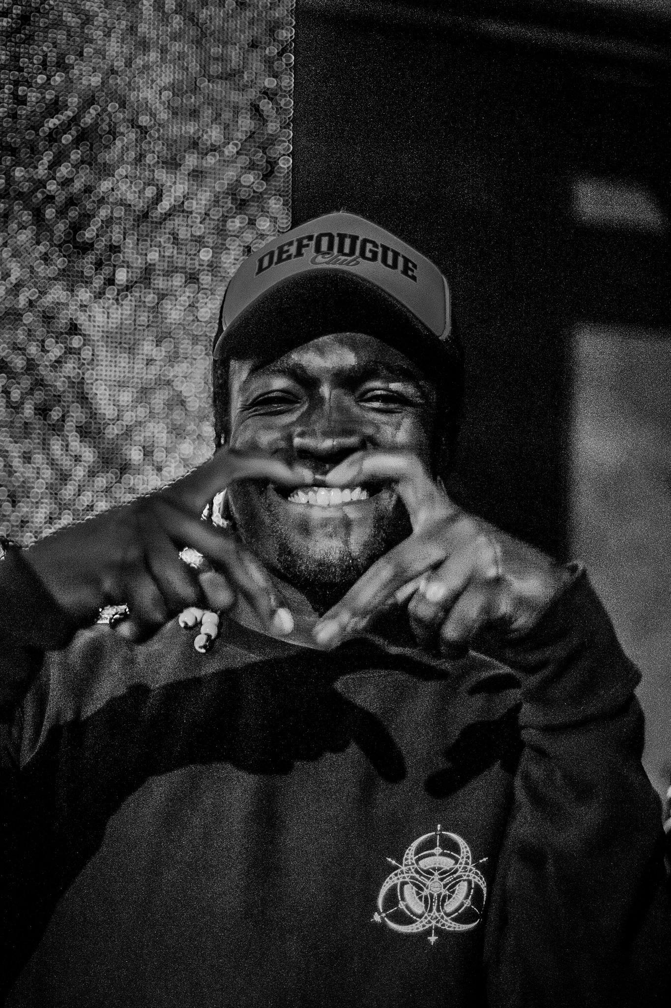 Un ami d'un DJ faisant le signe du coeur avec ses doigts en regardant la caméra.