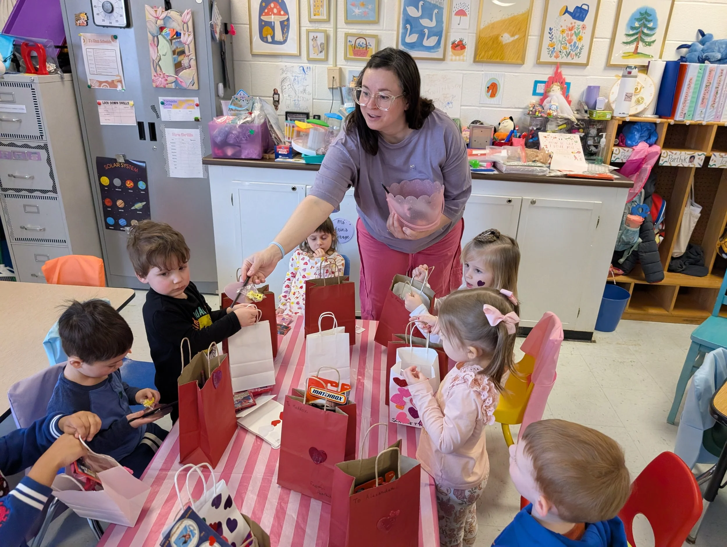 Teacher giving out gift bags to children during a classroom party.