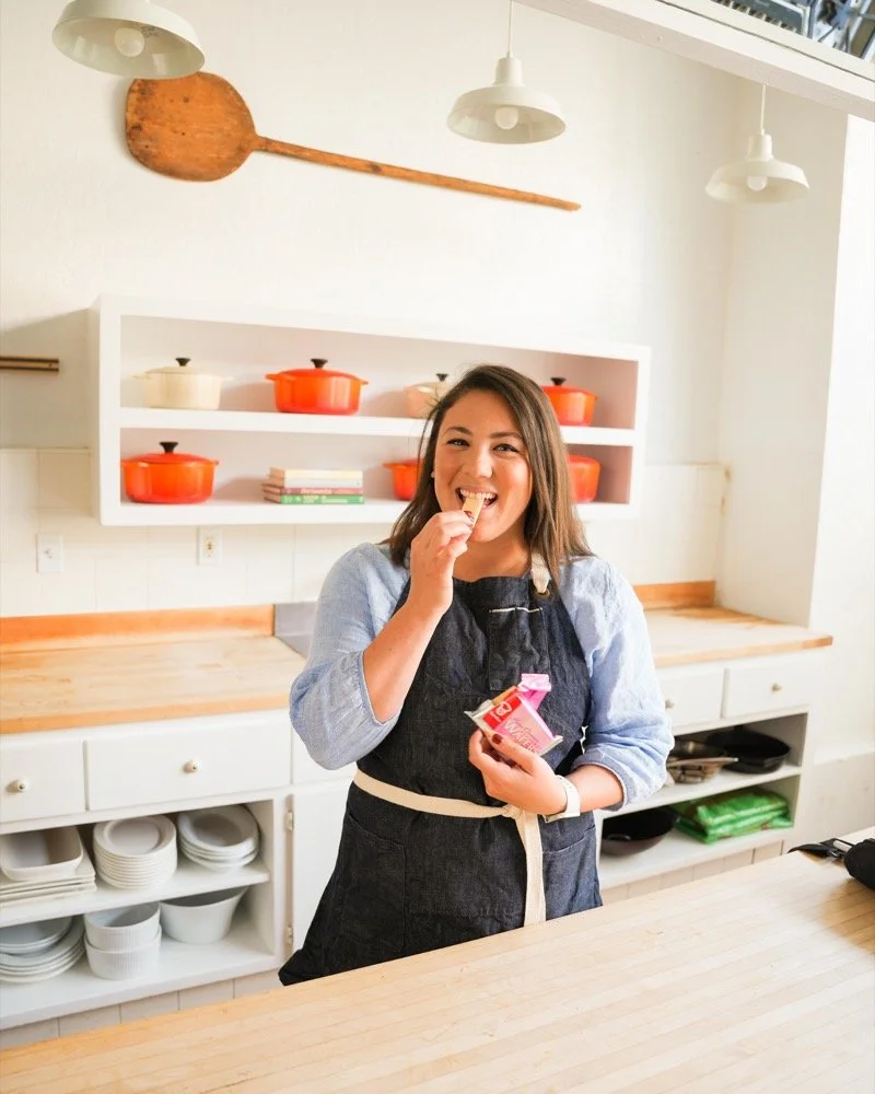 Erica Lovelace smiling and enjoying a wafer in her kitchen.