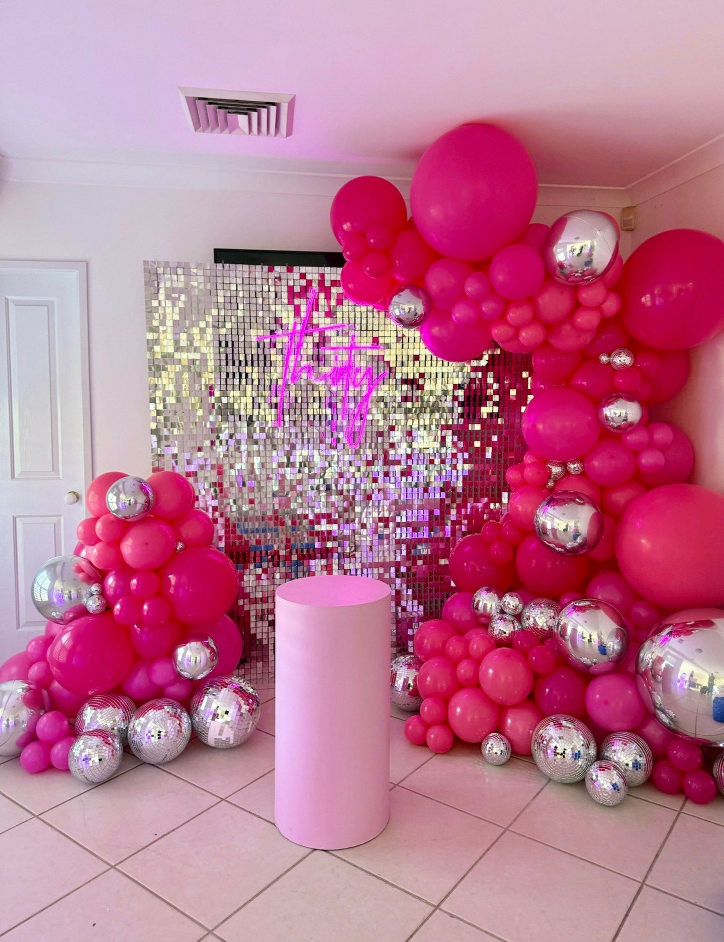 30 in Style ✨
This glamorous 30th set up features our silver shimmer wall, which always pairs beautifully with our neon signs. To top it all off, we included two bright pink balloon garlands with chrome accent balloons for a fun and striking celebrat
