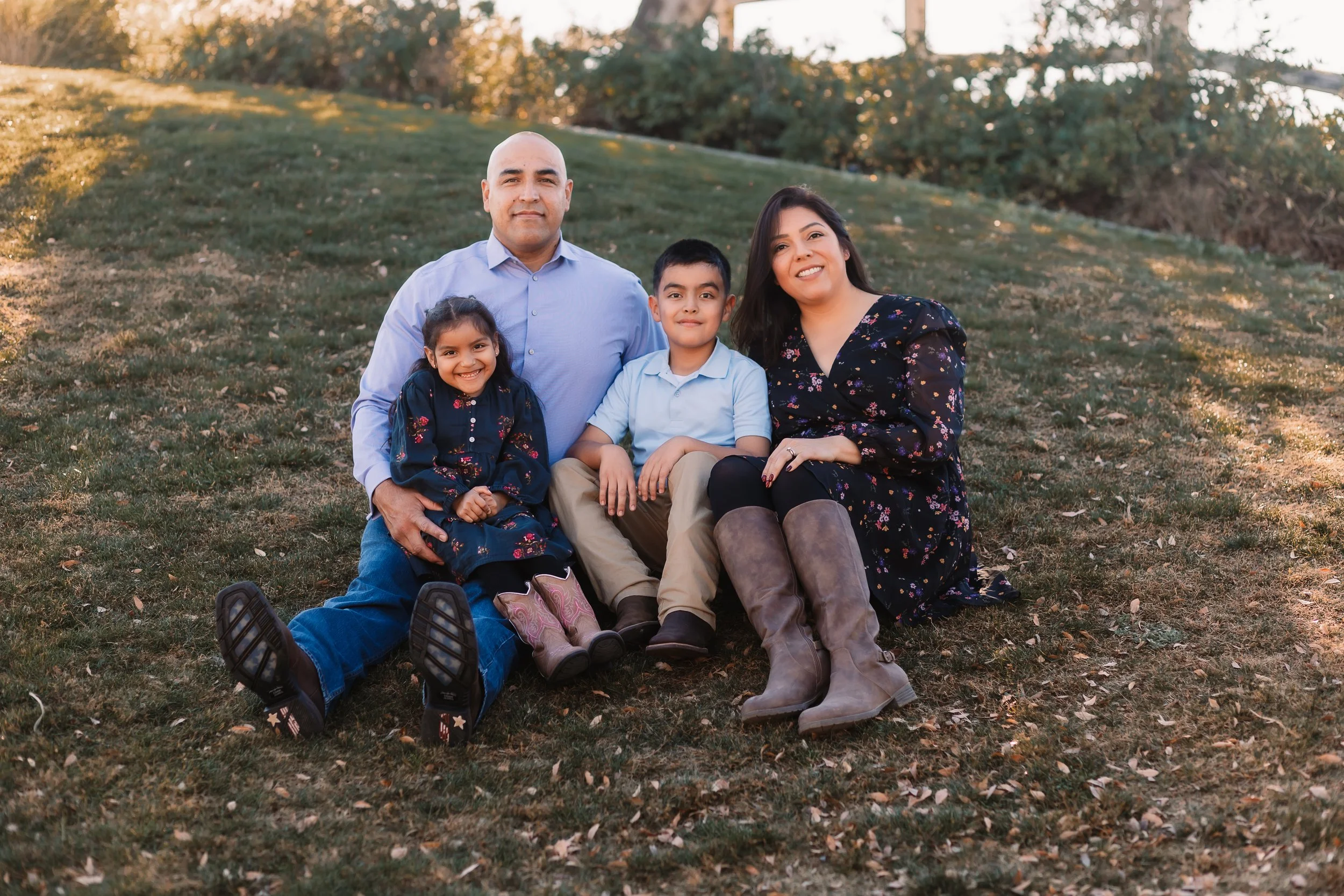 Family of four sitting together on grass at golden hour, Santa Clarita