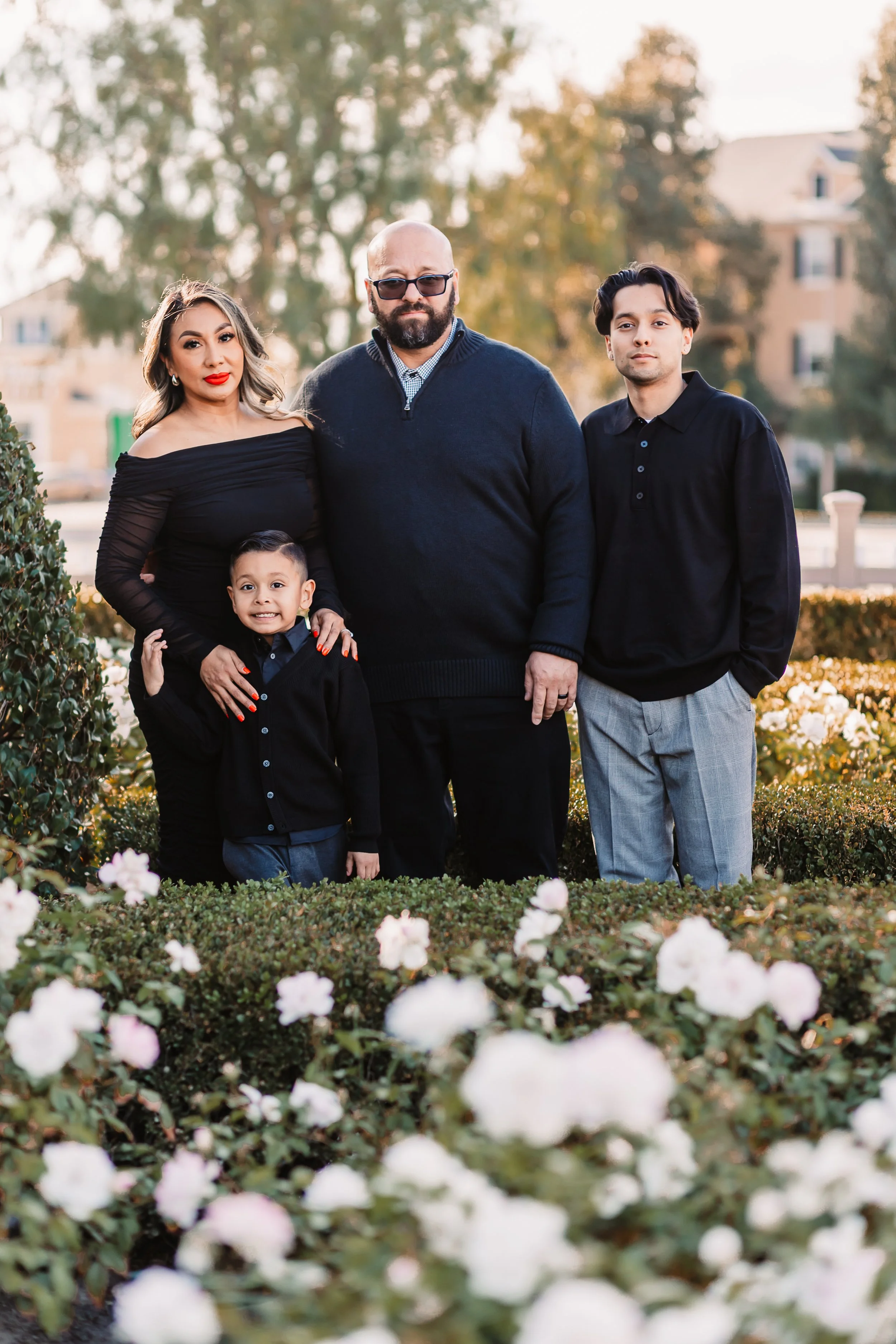 Family of four in black outfits posing among white flowers in a Santa Clarita park at golden hour