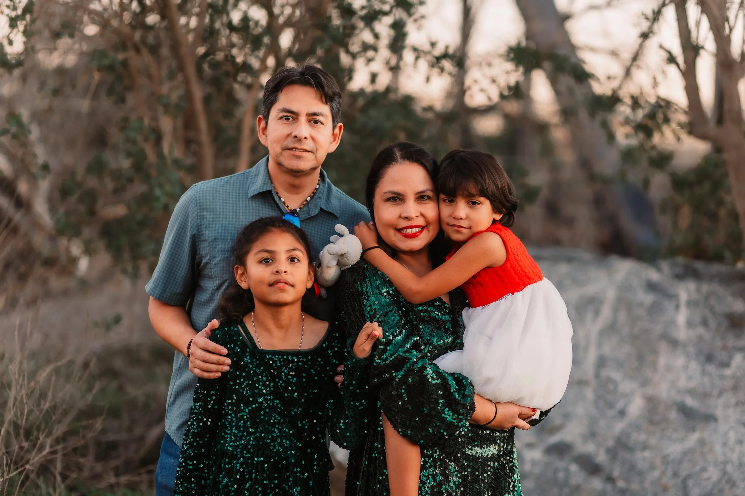 Family of four sharing a group hug outdoors at sunset, Santa Clarita
