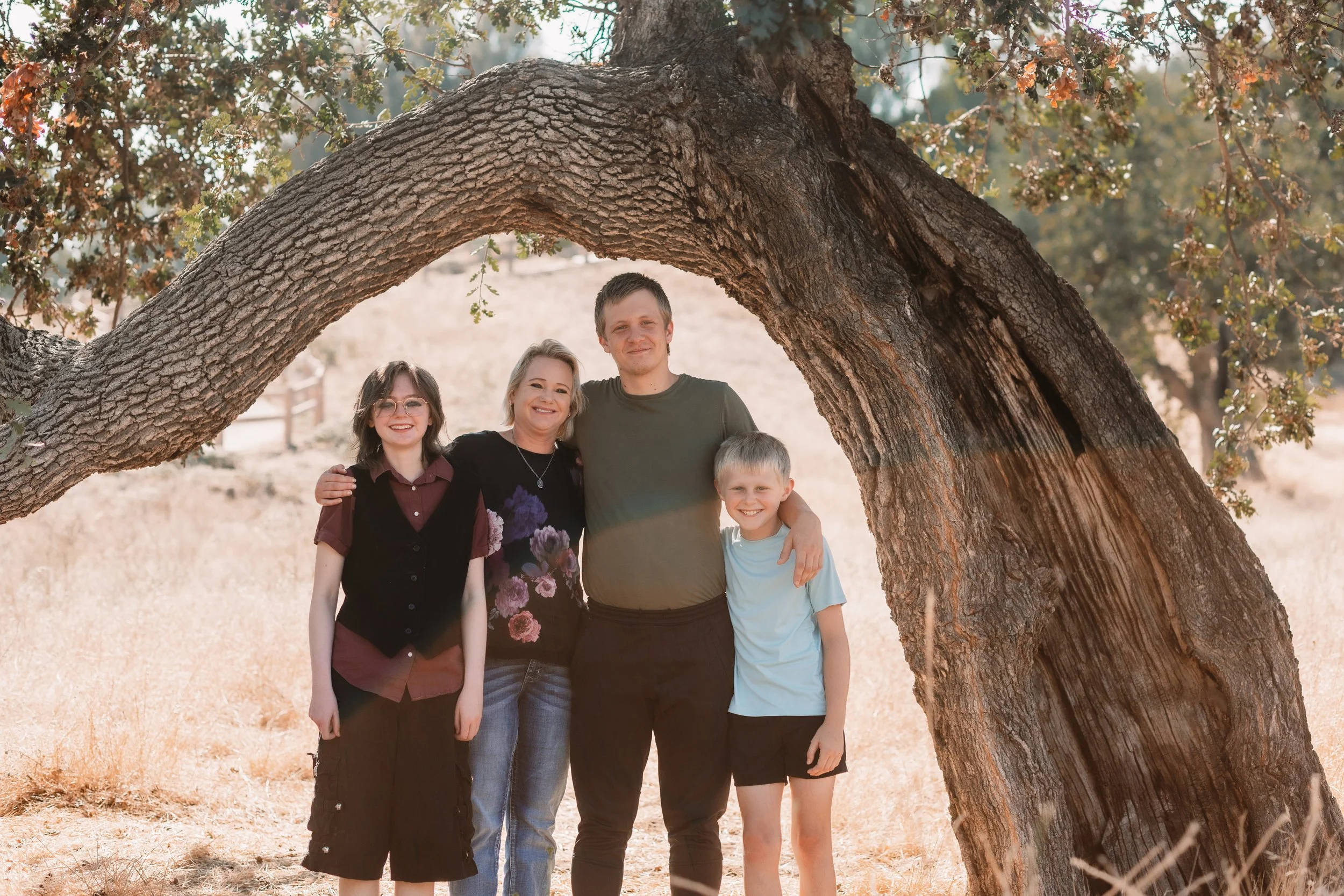 Family of four framed by an arched oak tree in Santa Clarita