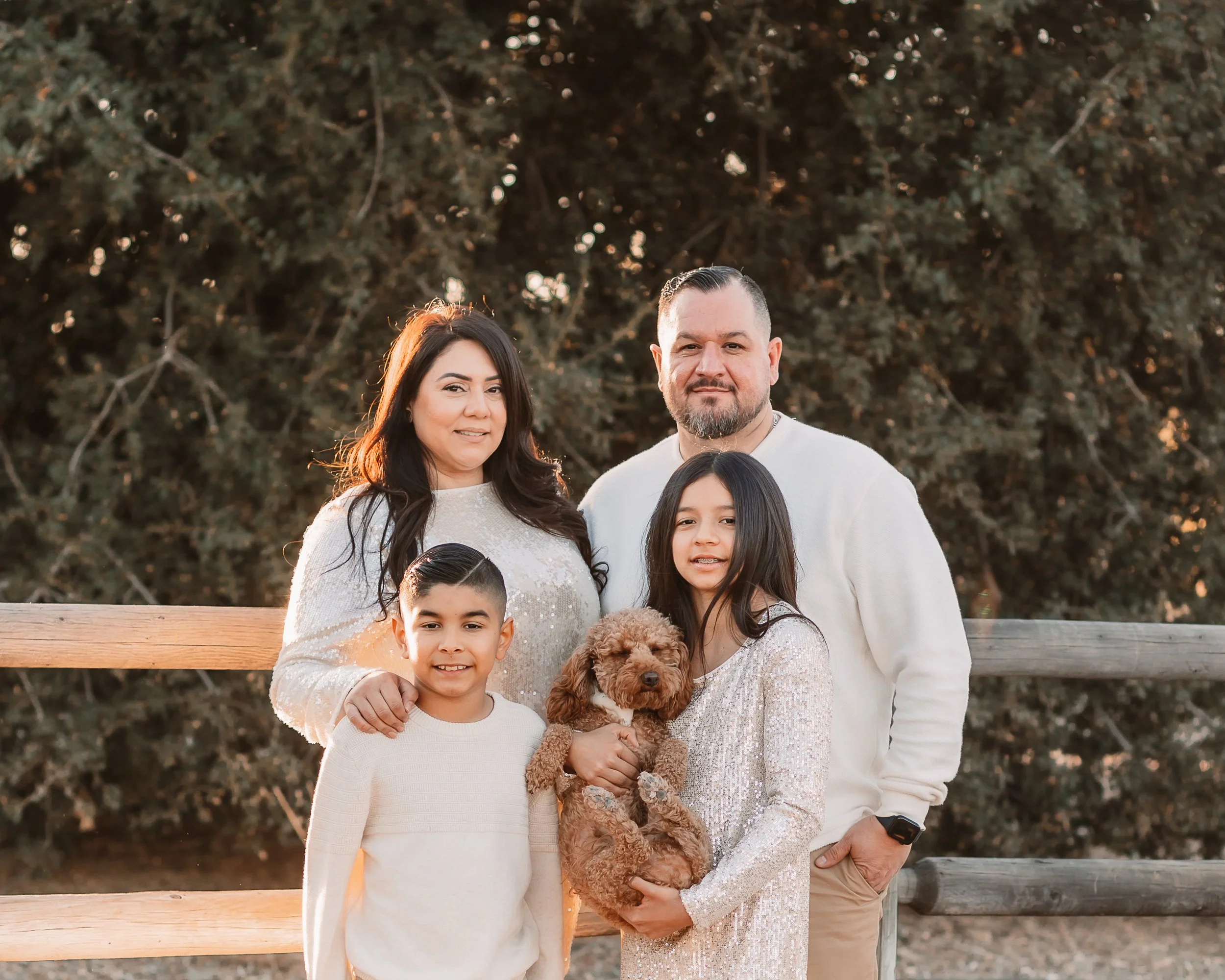 Family of four with their dog posing by a wooden fence in warm Santa Clarita evening light