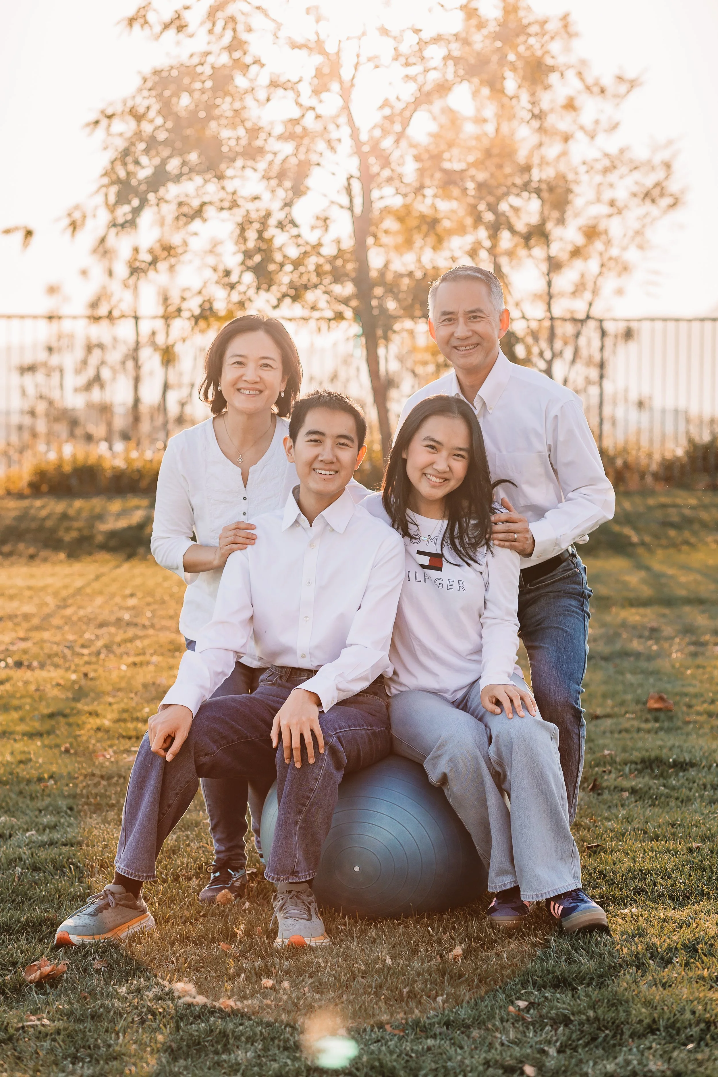 Family of four smiling together on green grass in warm Santa Clarita sunlight