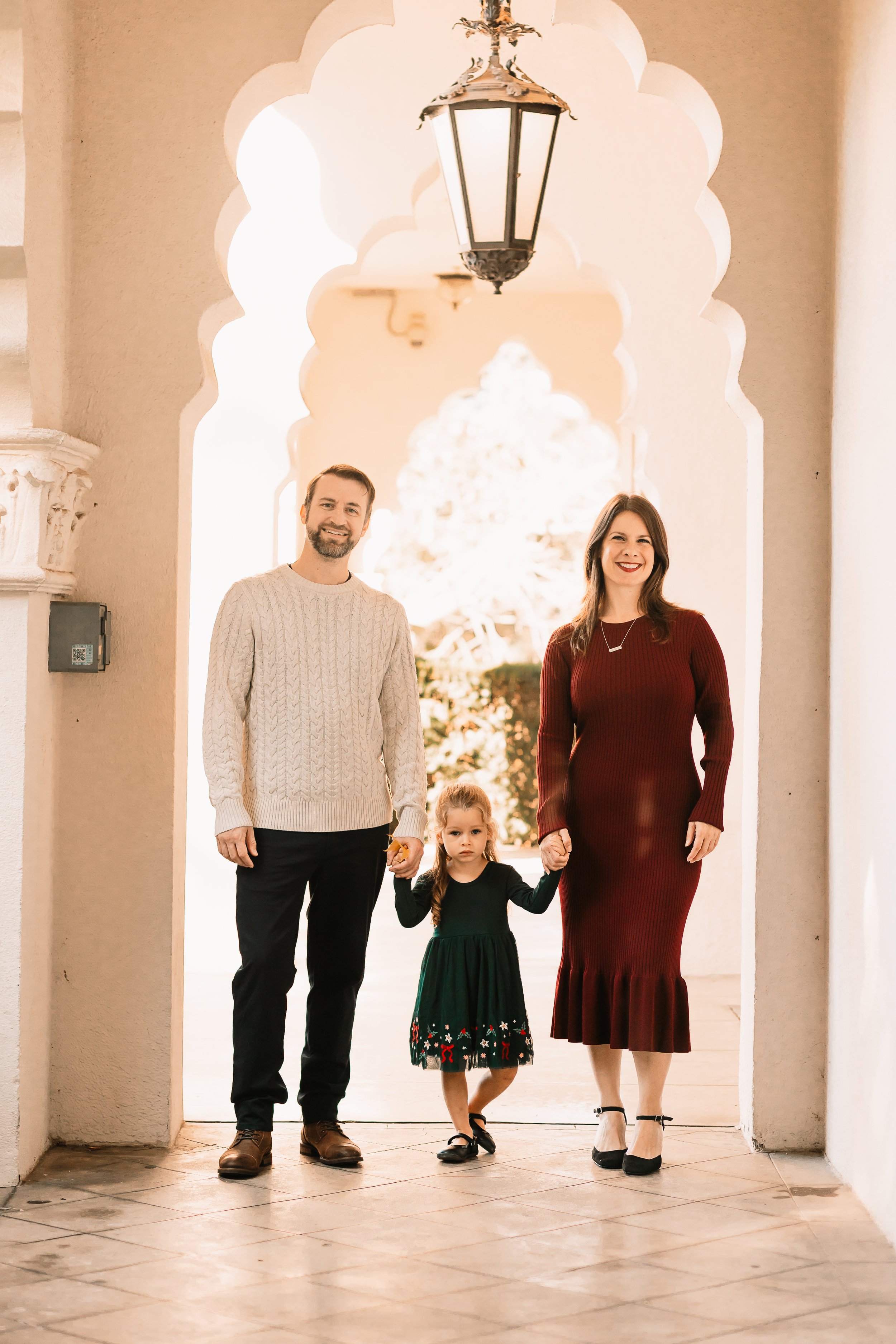 Family of three smiling under a grand stone archway, Santa Clarita