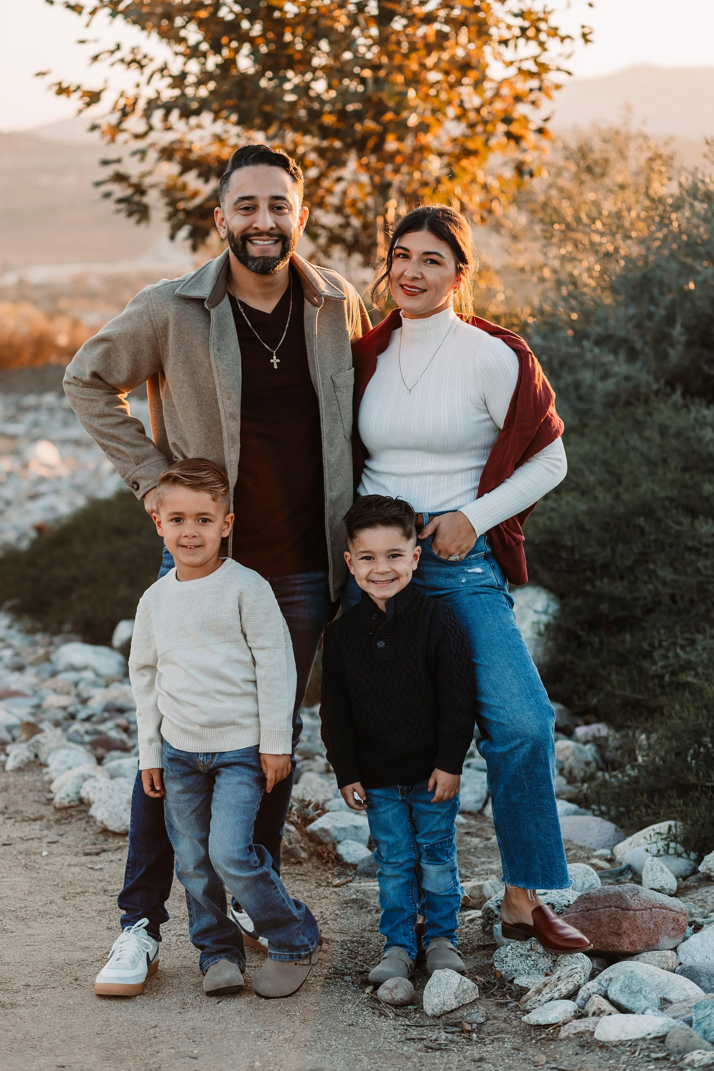 Family of four smiling at sunset on a rocky hilltop overlooking Santa Clarita