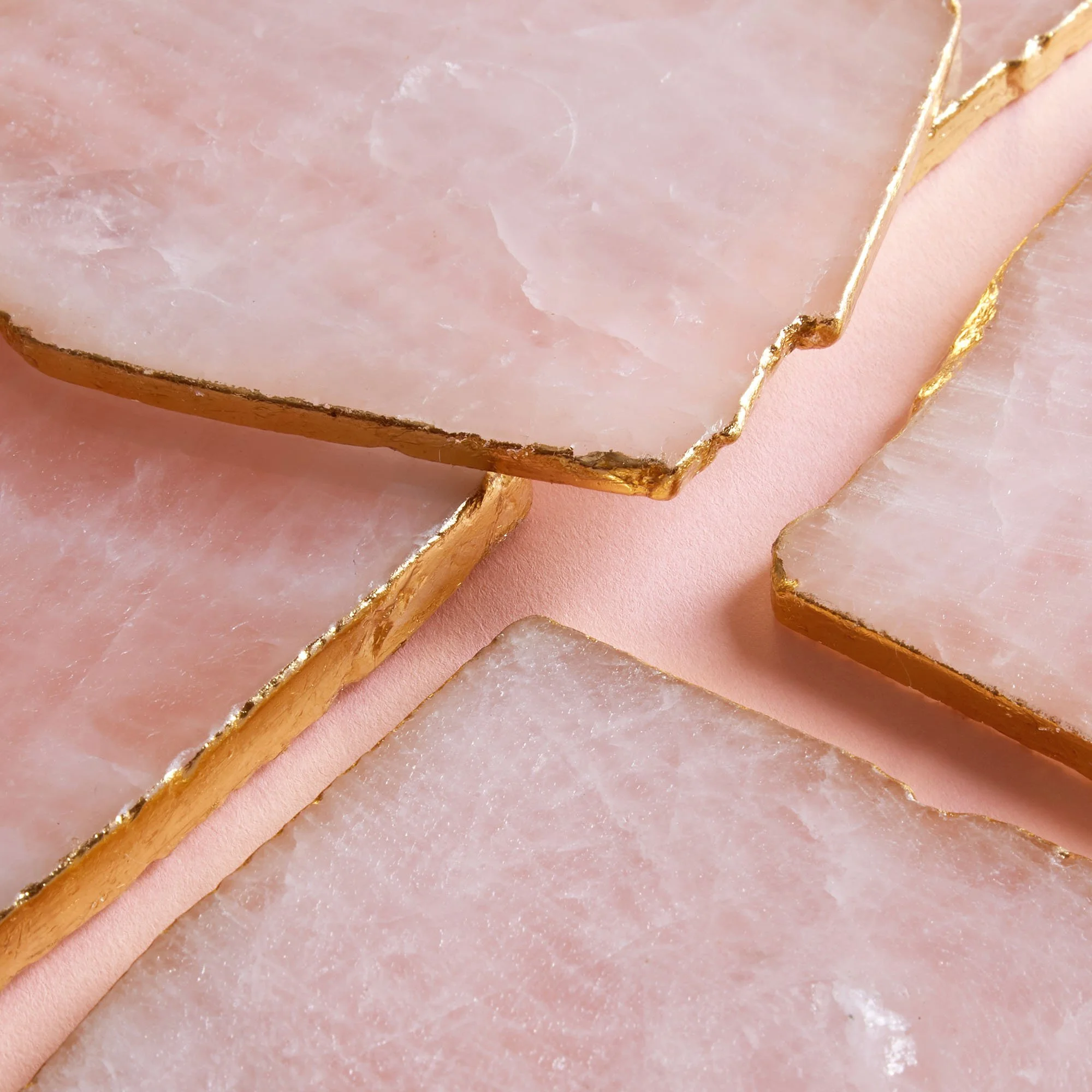 Close-up of pink and white marble slabs with gold edges on a soft pink background.