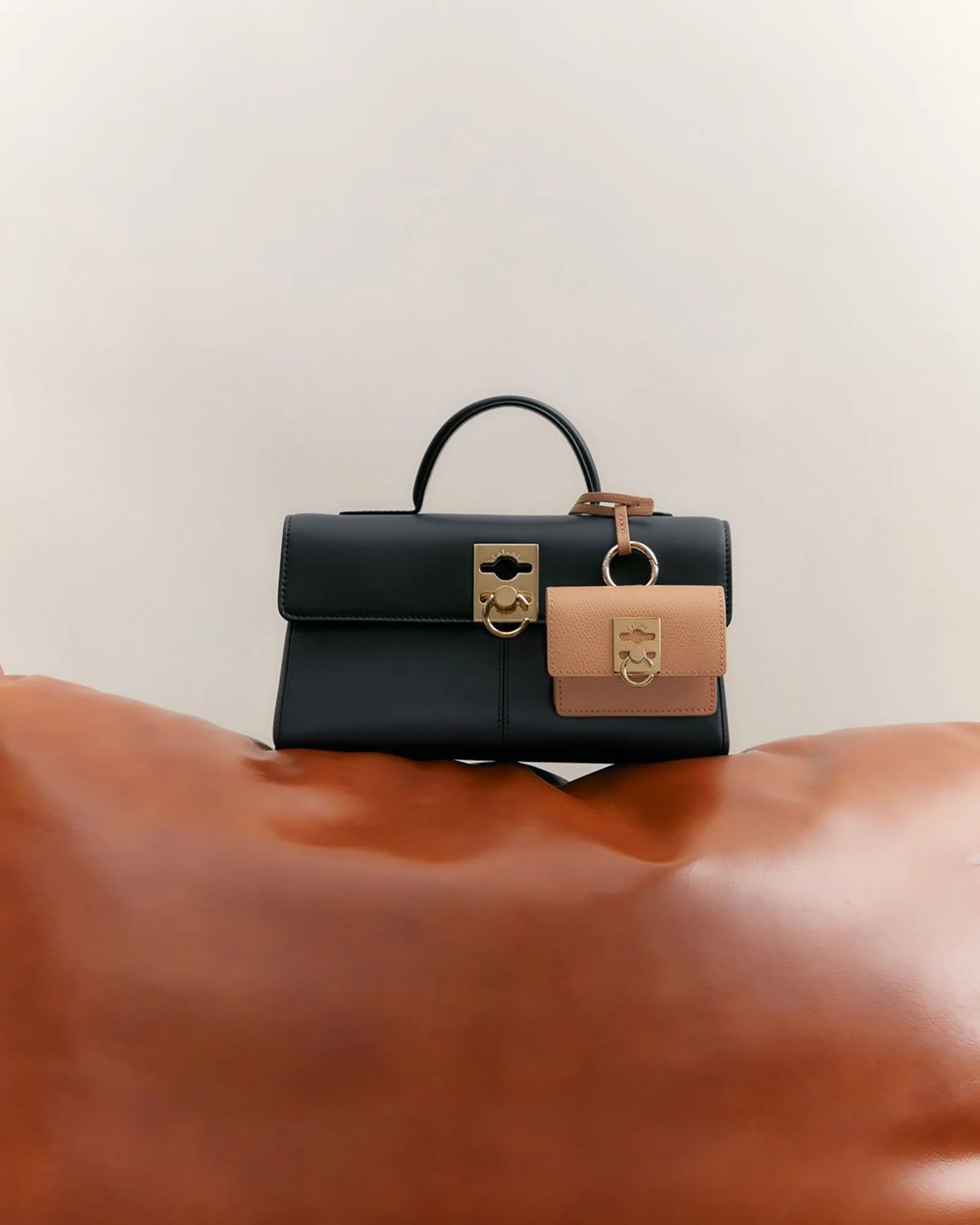 Multiple handbags of different colors and styles displayed against a plain background.