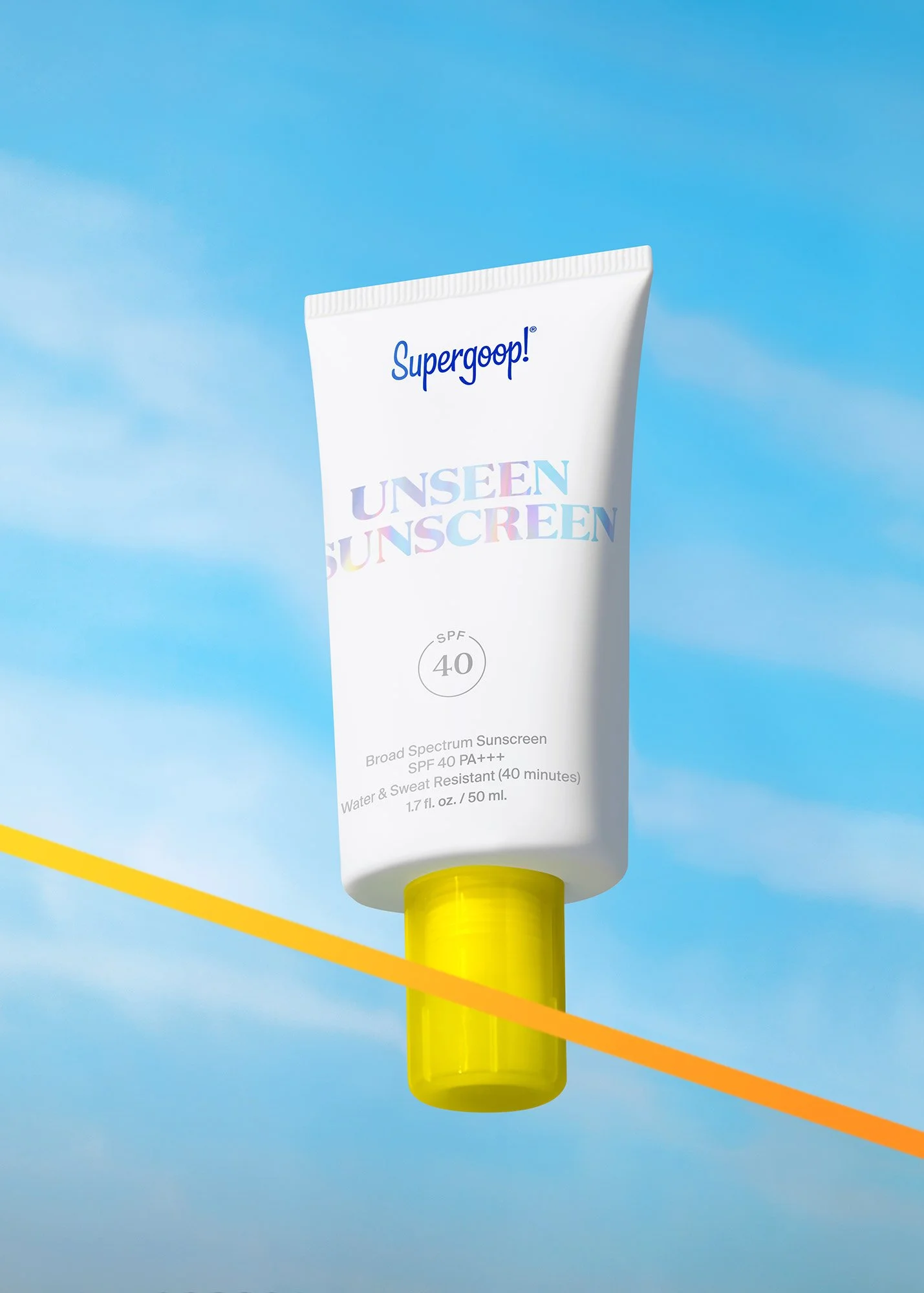 A white tube of Supergoop! Unseen Sunscreen with yellow cap, floating against a blue sky with clouds.