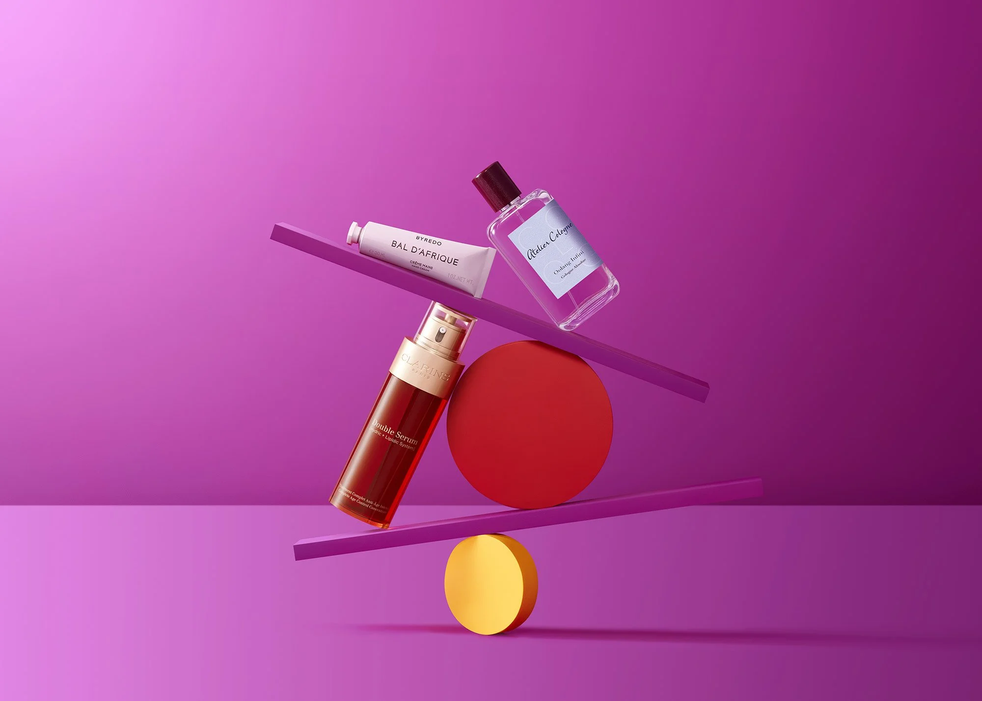 Arrangement of skincare and fragrance products, including a red serum bottle, a white tube of cream, a purple bottle of perfume, set on inclined pink and purple surfaces with geometric shapes in yellow and red.