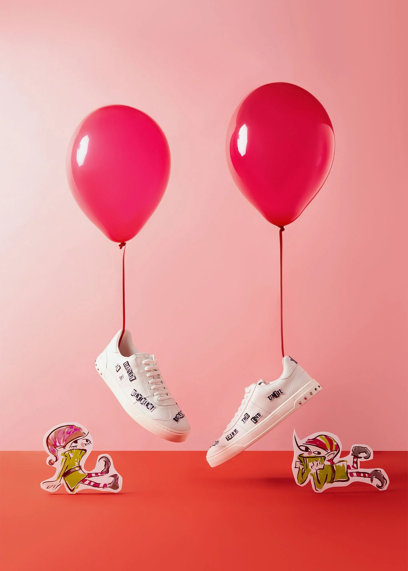 Two white sneakers with black lettering, suspended from pink balloons against a pink background, with cartoon stickers of girls at the bottom.