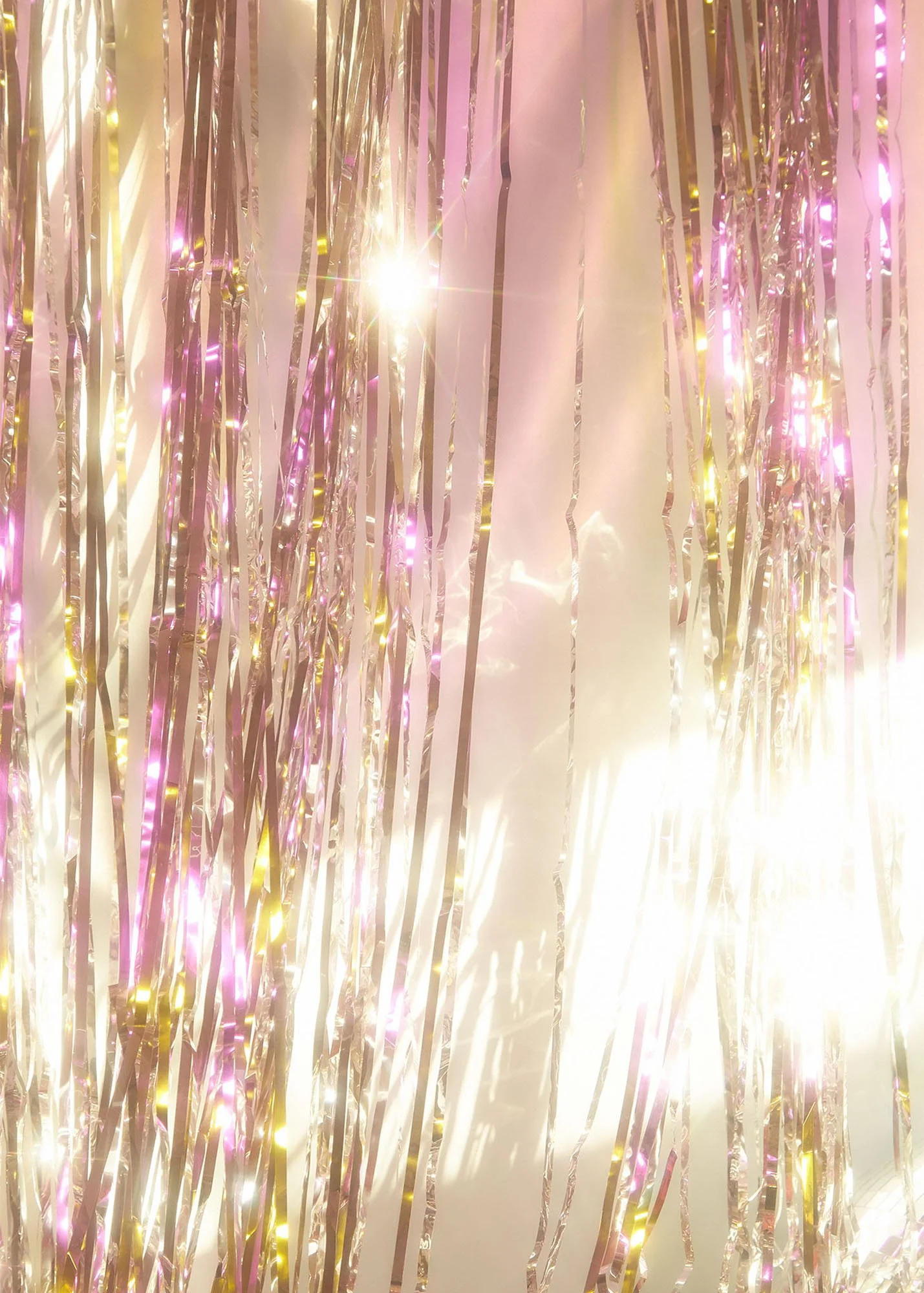 Pink, gold, and white tinsel with lights, creating a festive decoration.