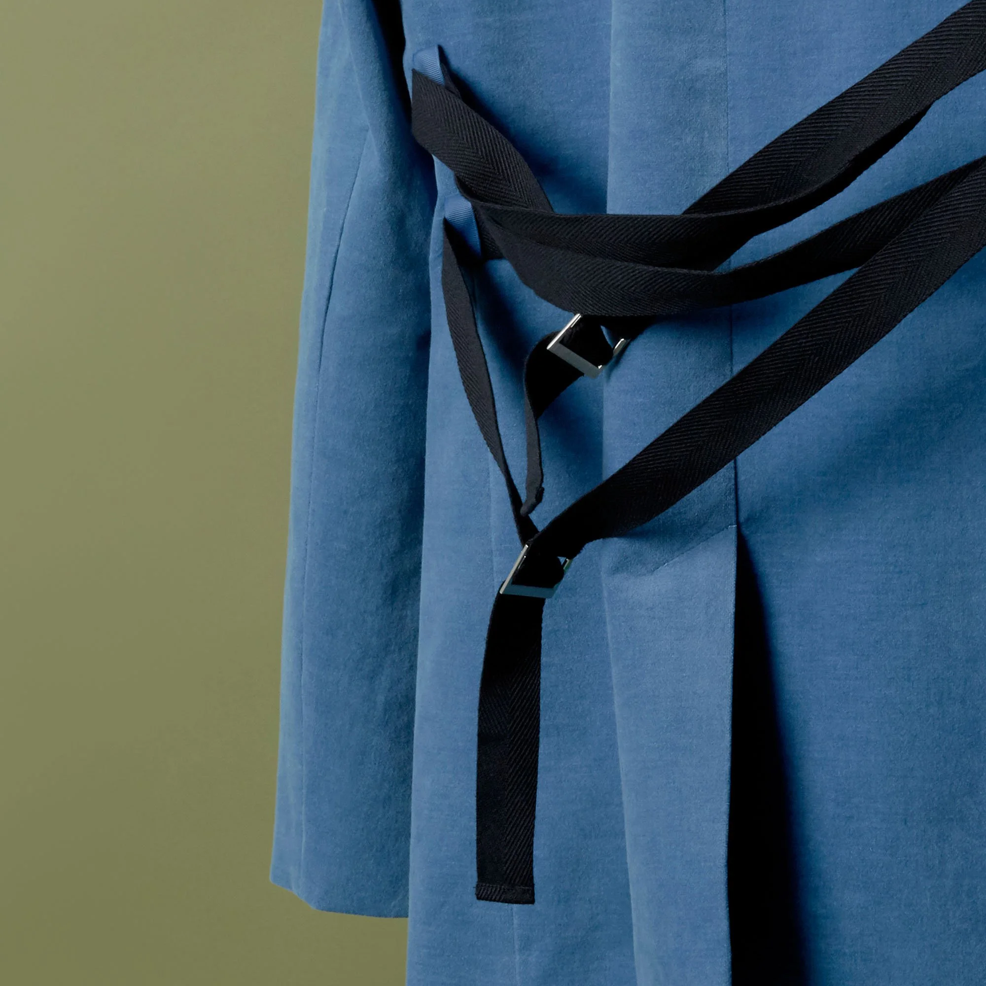 Close-up of a person wearing a blue coat with a black strap hanging from the shoulder.