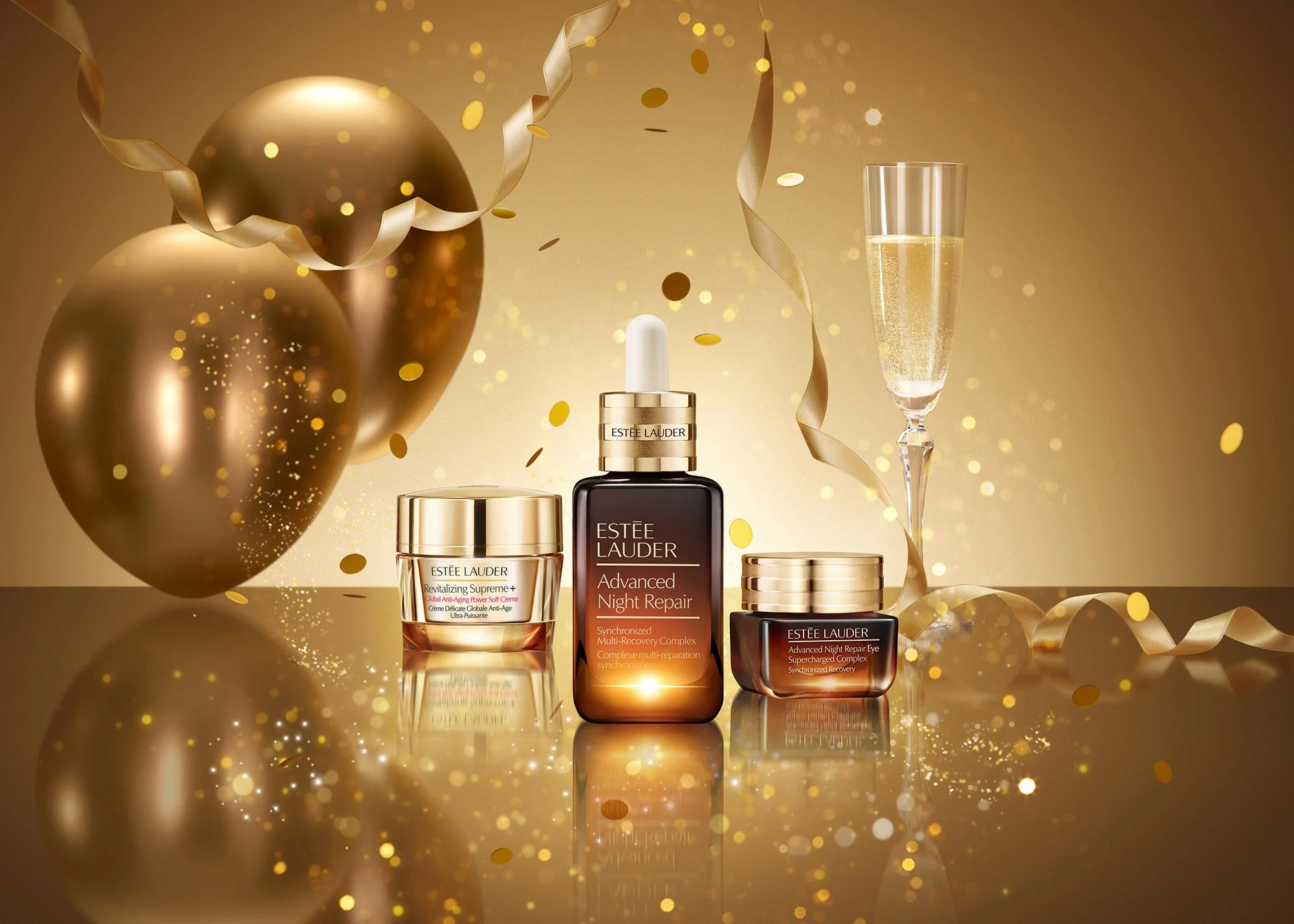 Beauty products from Estée Lauder including Revitalizing Supreme, Advanced Night Repair serum, and another jar, with balloons, confetti, and a glass of champagne for a celebratory setting.
