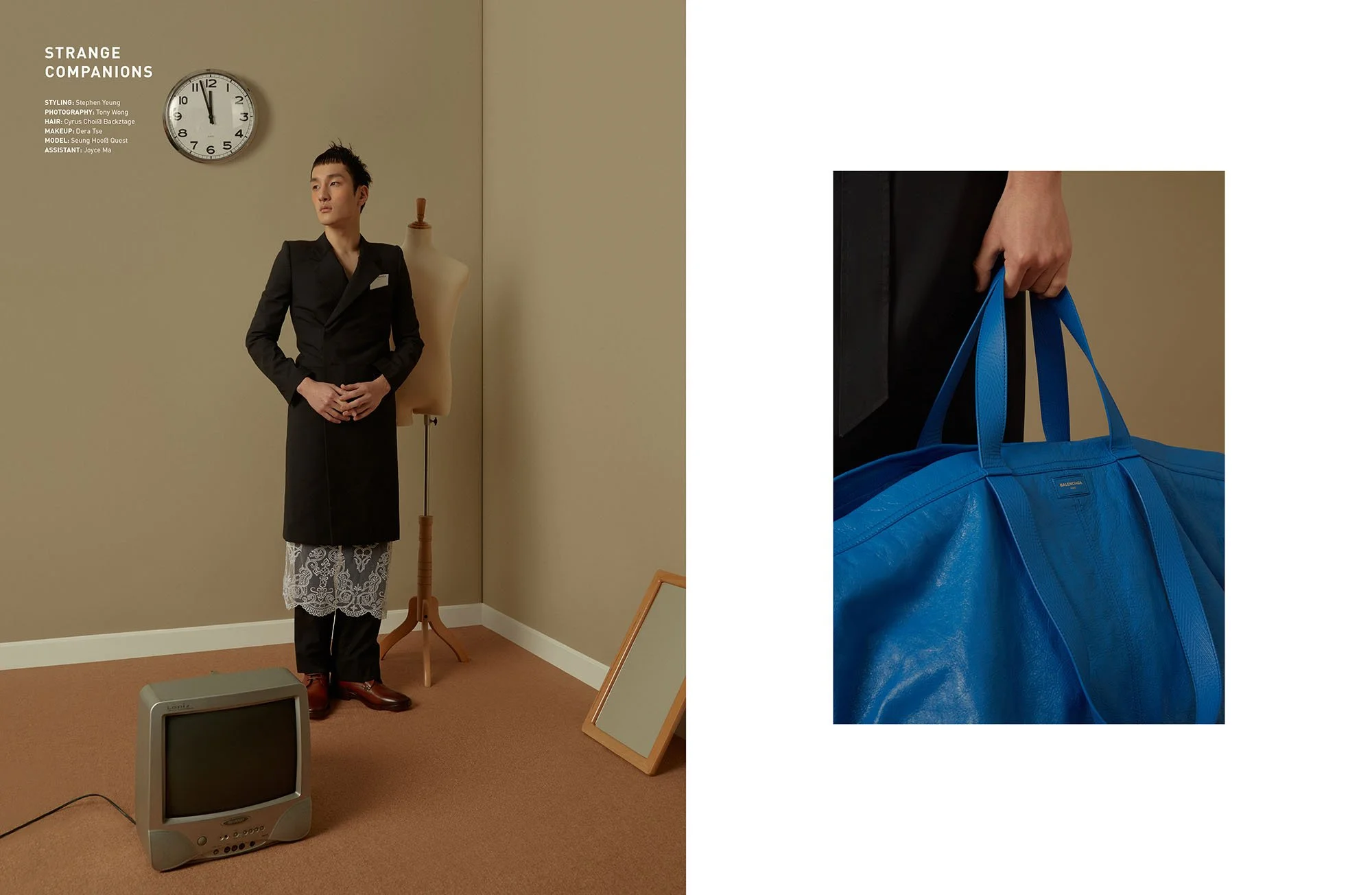 A person dressed in a black jacket, lace skirt, and black pants holding a blue bag, standing in a room with a clock on the wall, a mannequin, a mirror, an old television, and a beige wall.