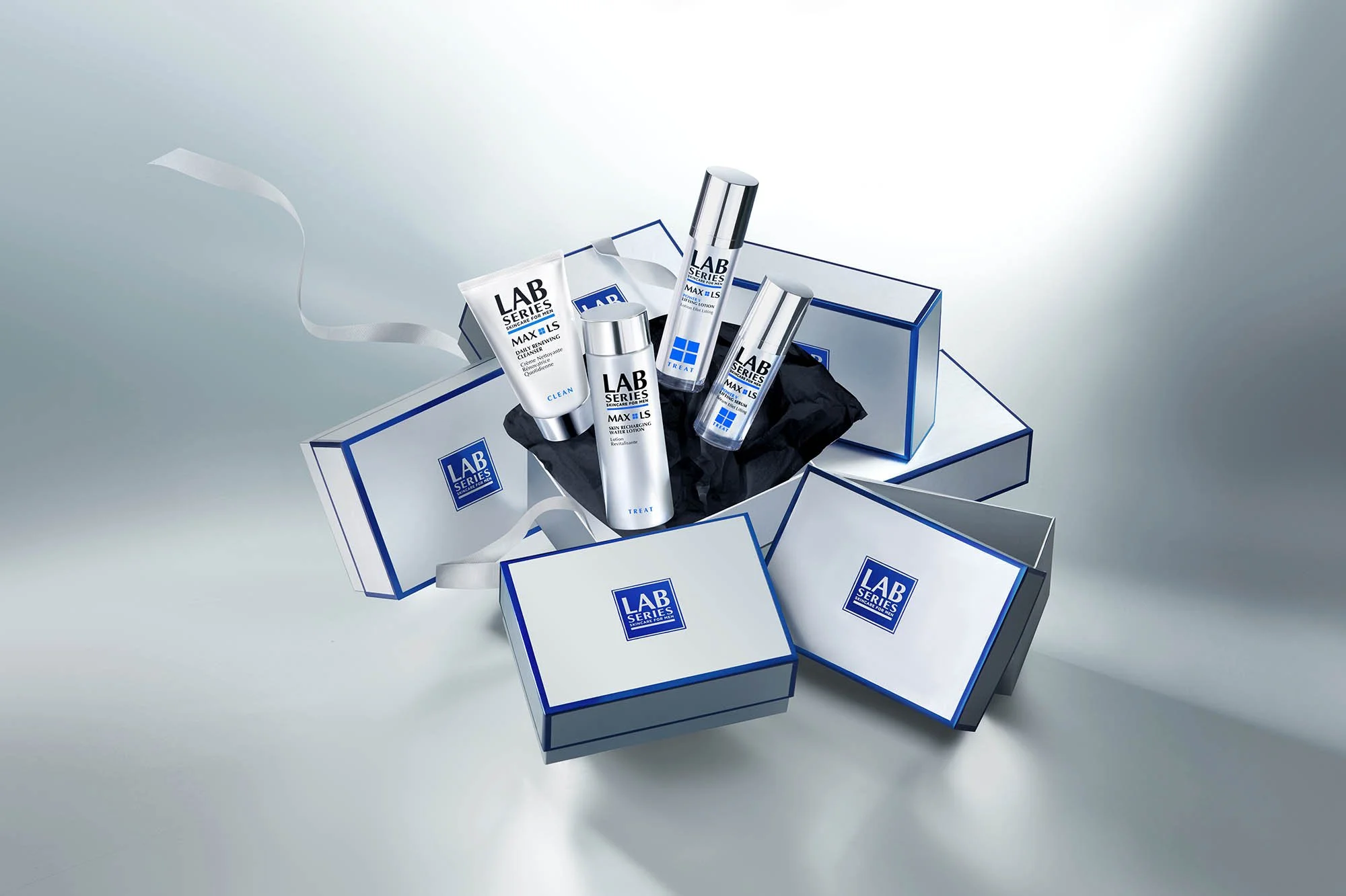 Skincare products from Lab Series, including cleansers and lotions, arranged on a reflective surface with some boxes and tissue paper.