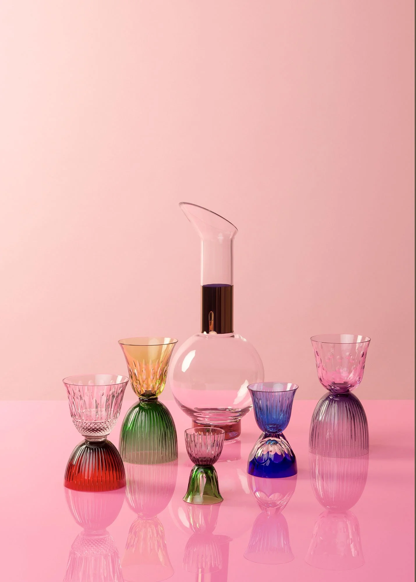 Colorful glassware including a tall glass vase with dark liquid, and various small, ribbed glasses in pink, green, yellow, purple, and blue, arranged on a pink surface with a pink background.