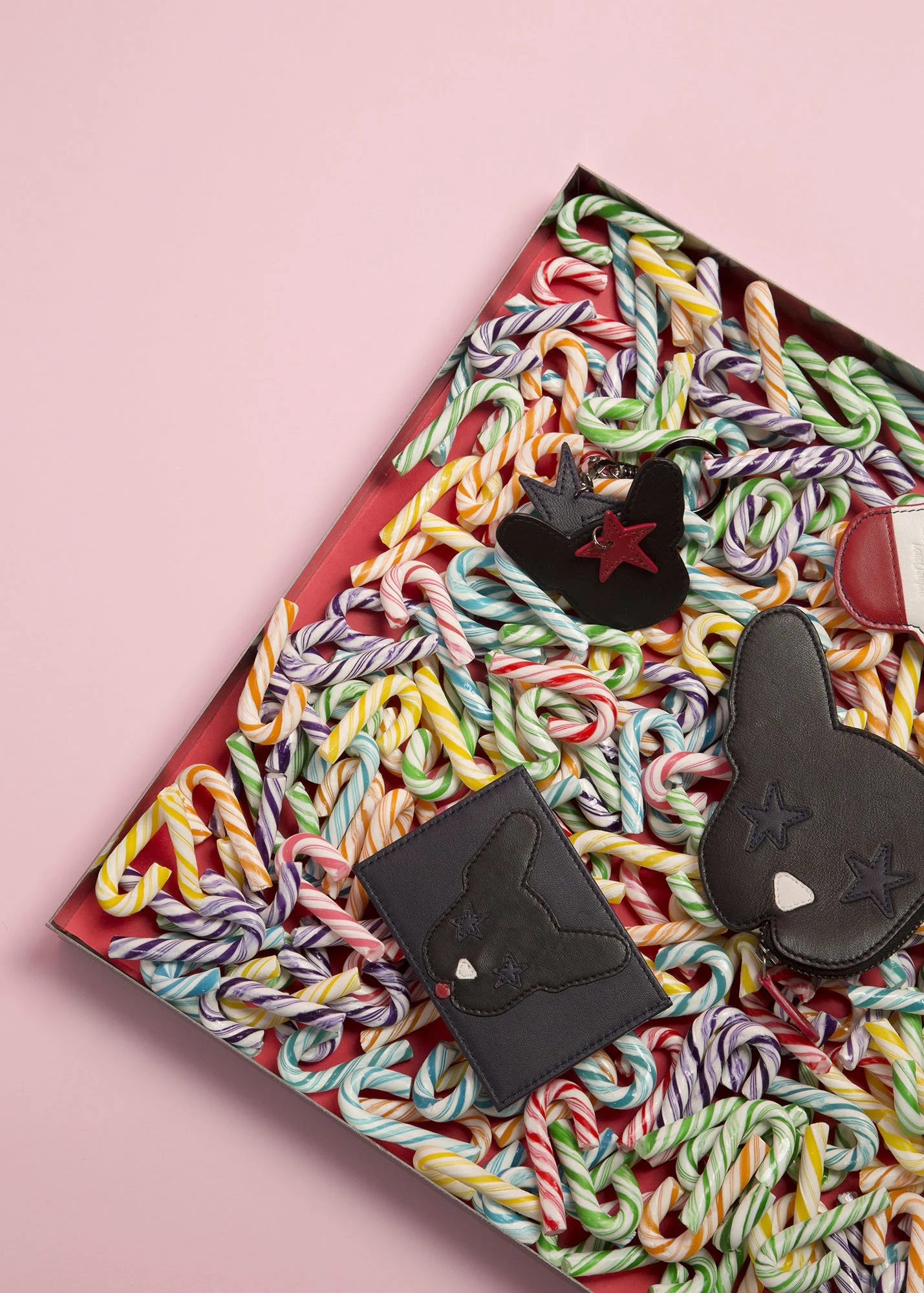 Colorful candy canes in a box with cute plush animal keychains on top.