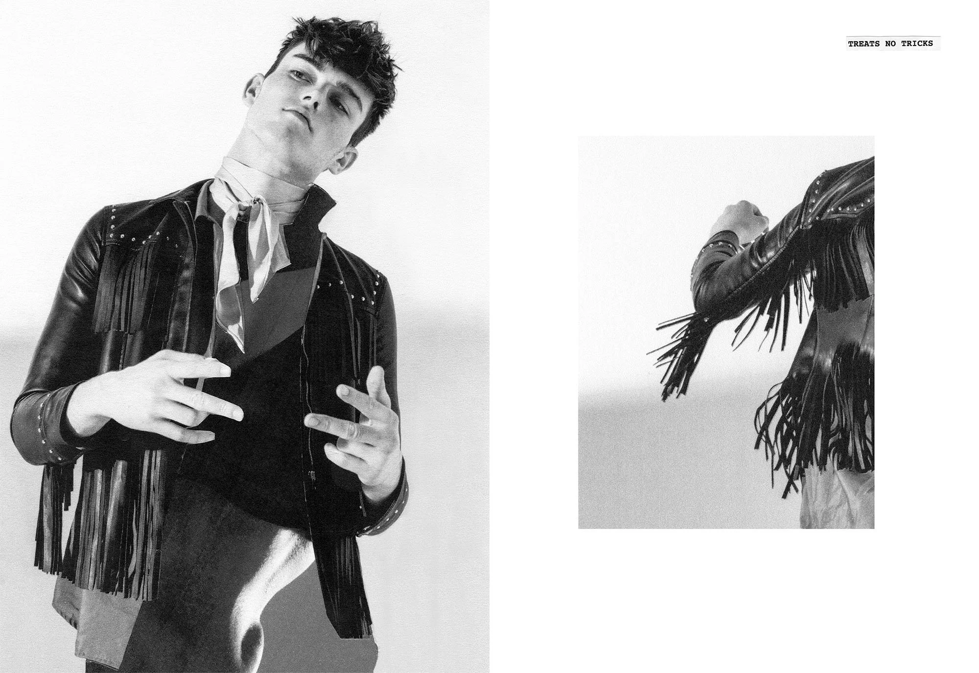 Black and white photo of a young man with tousled hair, wearing a leather jacket with studs, making a peace sign with his hand. Partial image of a person in fringe clothing, holding a cigarette, is visible on the right.