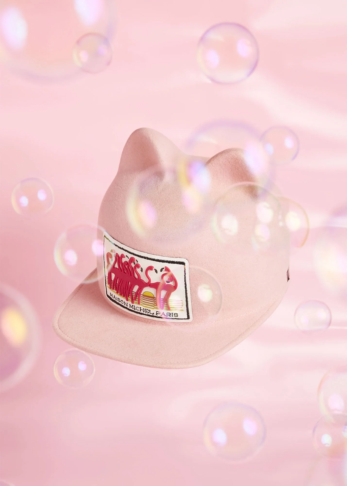 A pink baseball cap with a flamingo graphic and the text 'Cages C'est La Vie' on a pink background with floating bubbles.