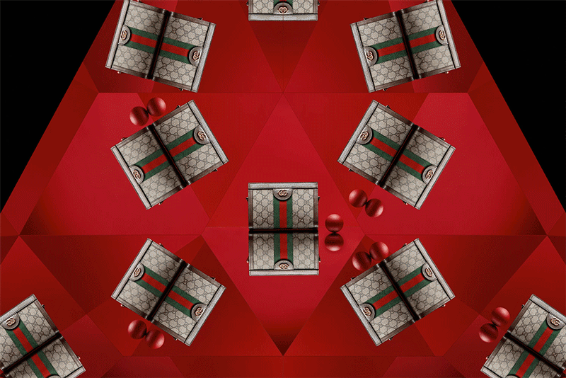 Multiple luxury cosmetic or jewelry boxes with Gucci designs and green-red-green stripes, arranged on a red geometric-patterned surface with red decorative balls.