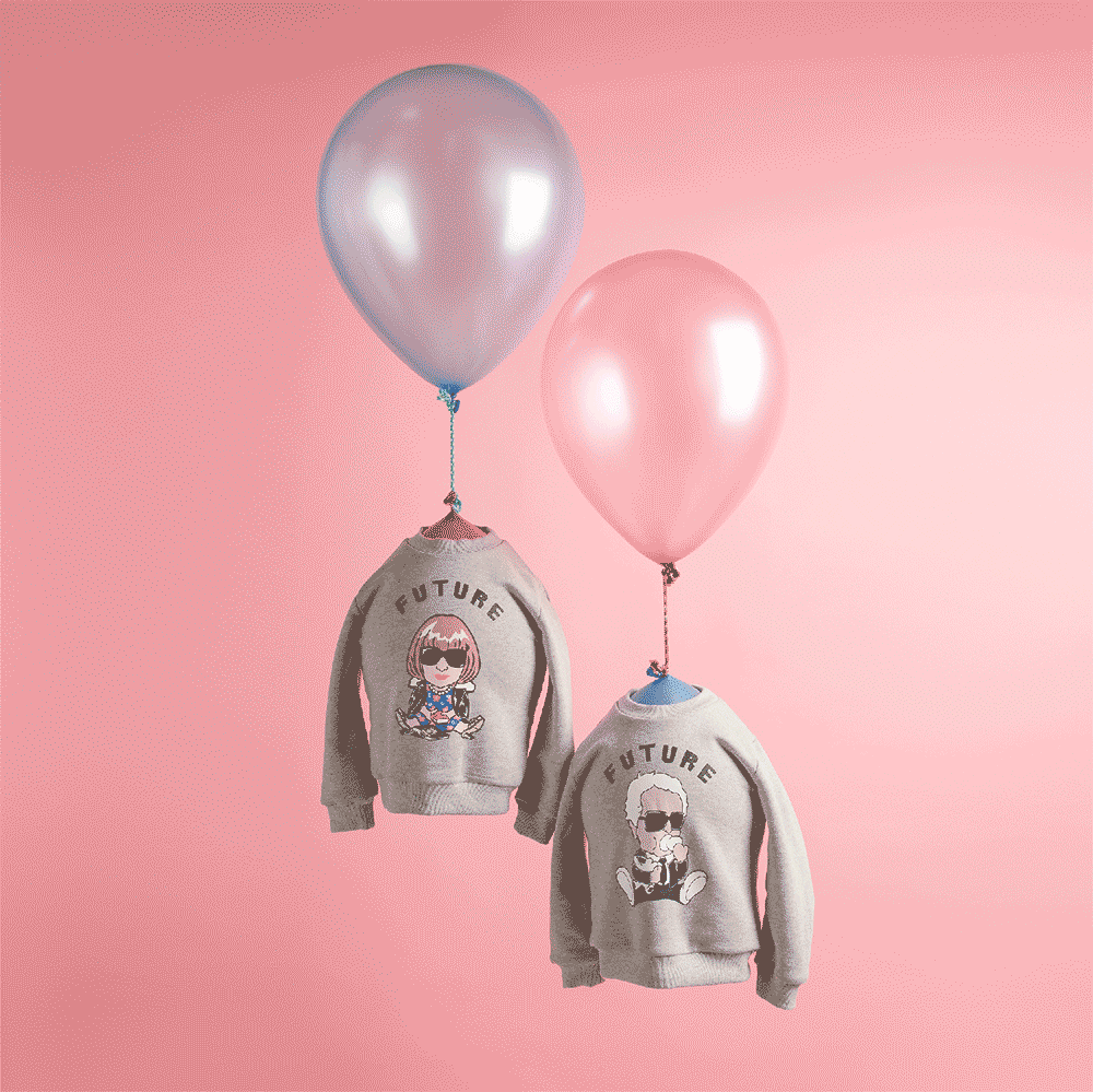 Two children's sweatshirts with cartoon graphics and the word "FUTURE" on a pink background, each attached to a metallic balloon, one silver and one pink.