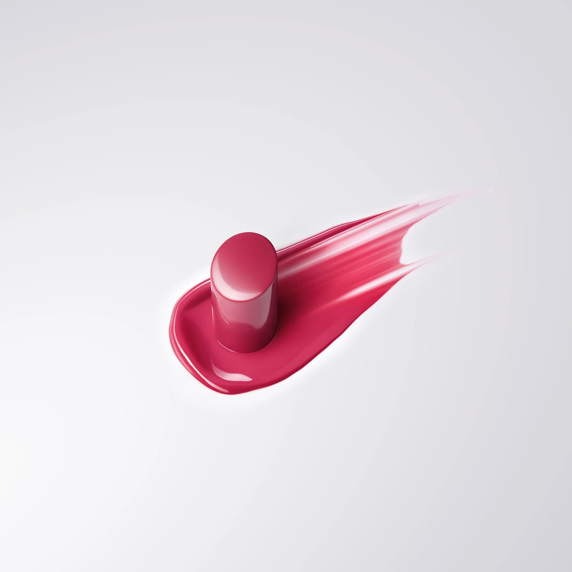 Close-up of a pink lipstick with a streak of pink lipstick lipstick in the background