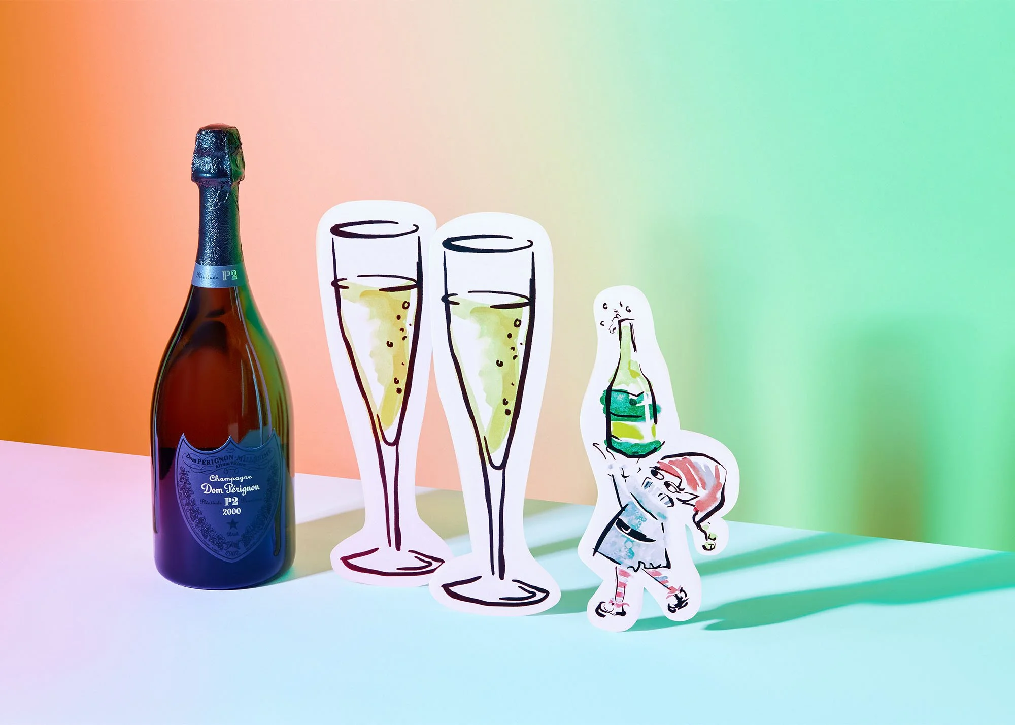 Photograph of a champagne bottle next to two illustrated champagne glasses and a cartoon character holding a champagne bottle and a glass, on a colorful pastel background.
