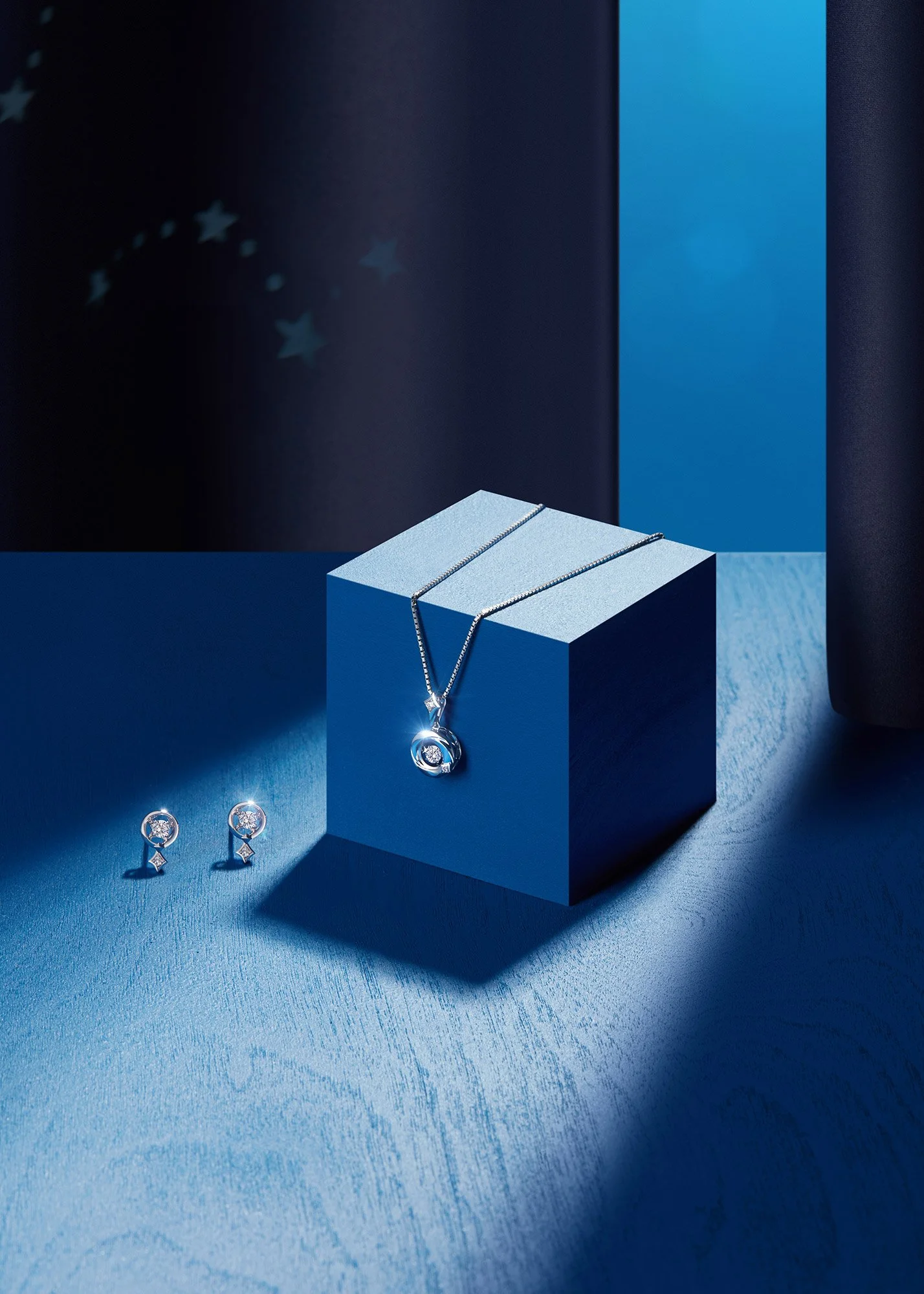 Silver jewelry set includes a necklace with a pendant and matching earrings, displayed on a blue geometric platform with dark and light blue backgrounds.