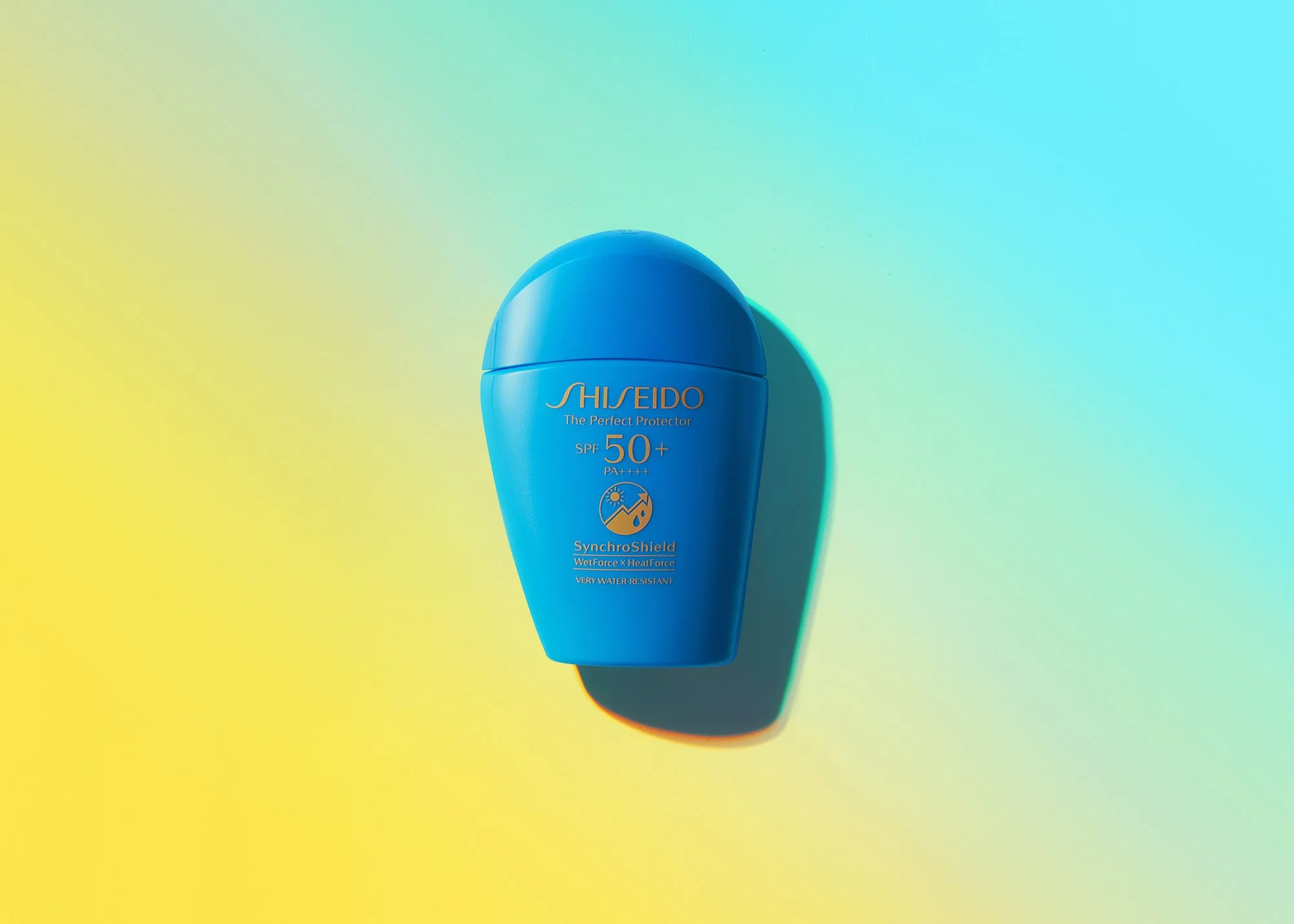 Blue bottle of Shiseido sunscreen with SPF 50+ and PA++++, labeled SynchroShield wet force and heat force, on a colorful gradient background with a shadow.