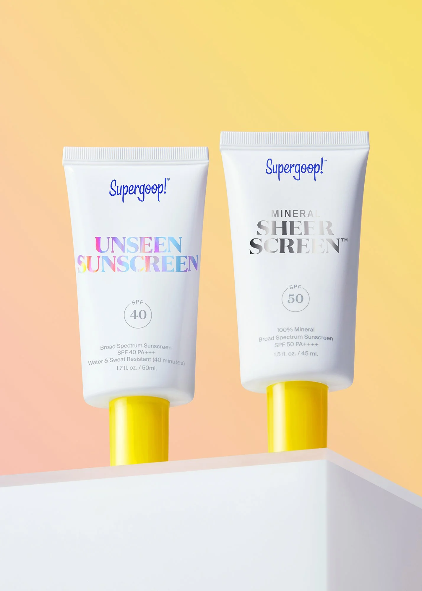 Two tubes of Supergoop! sunscreen, one labeled 'Unseen Sunscreen SPF 40' and the other 'Mineral Sheer Screen SPF 50', are standing upright against a pastel background.