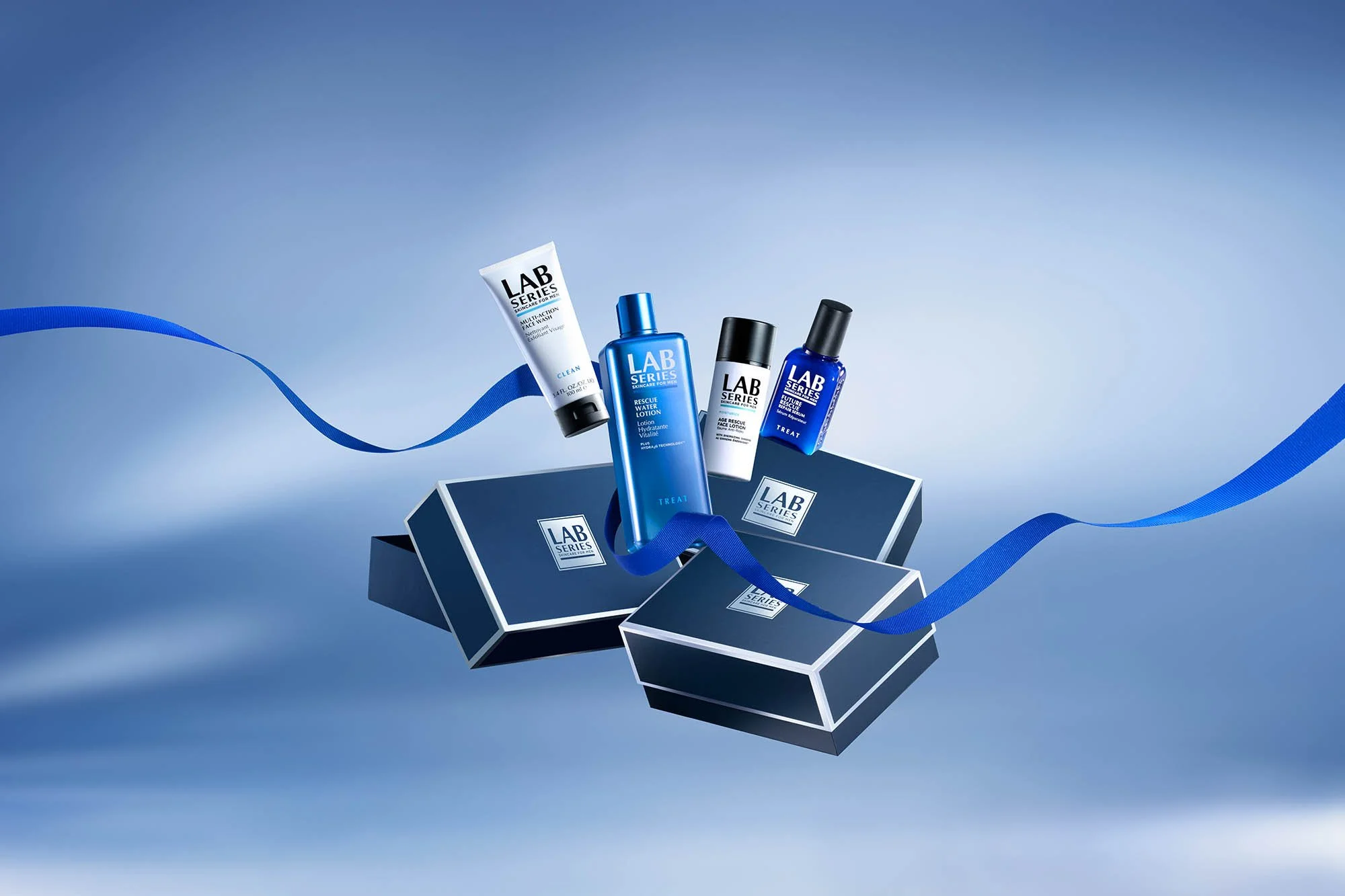 Skincare products from the Lab Series brand arranged on blue boxes with a blue ribbon, against a light blue background.