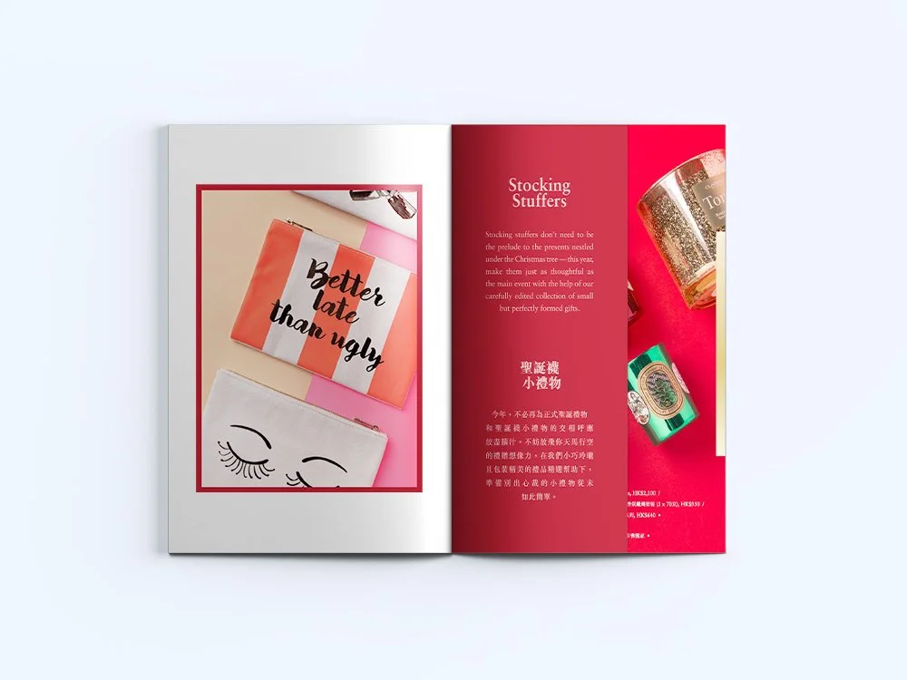 Open magazine showing products including a pink and orange striped pouch with the phrase 'Better late than ugly,' a white pouch with closed eyes and eyelashes, and three small decorative candles on a vibrant pink background.