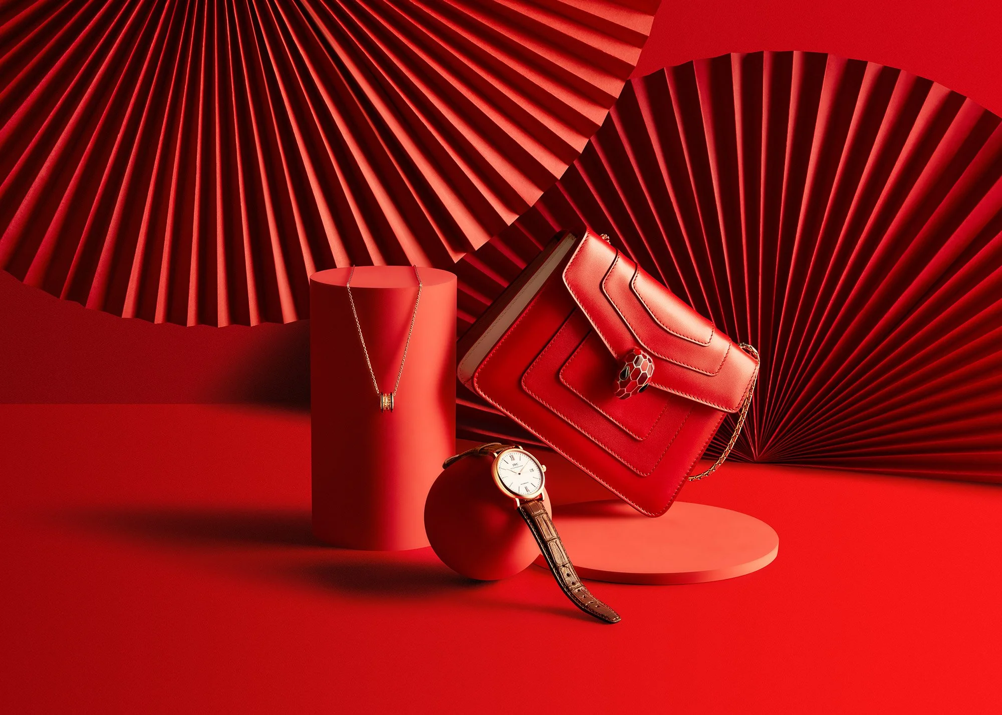 Red handbag, wristwatch, and necklace on red pedestals against a red geometric background.