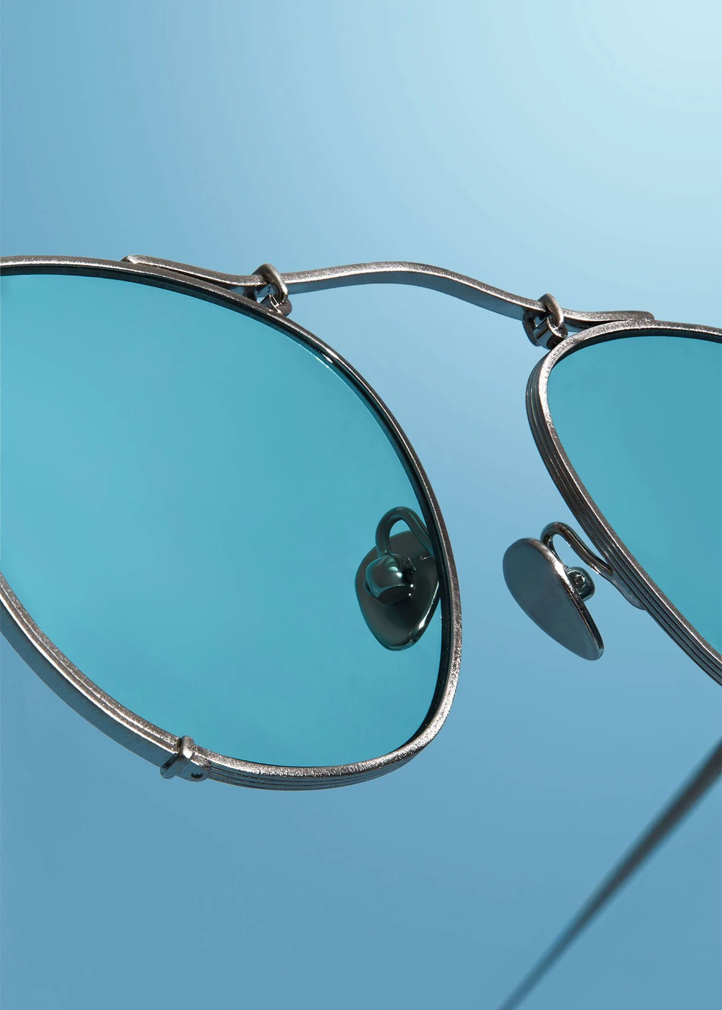 Close-up of a pair of sunglasses with metallic frames against a blue background.