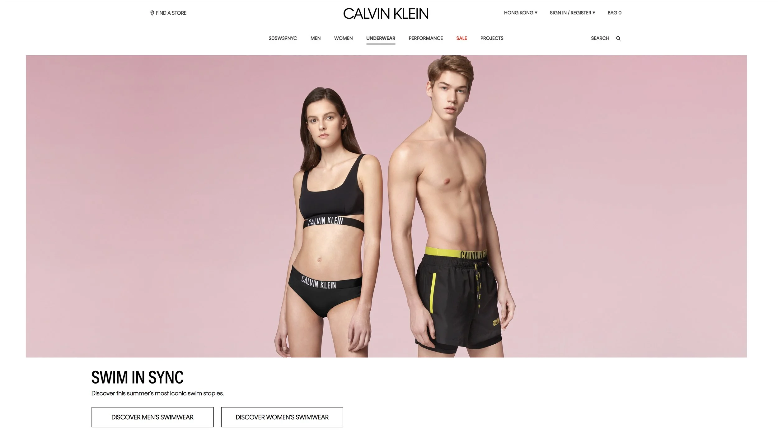 Two models, one female and one male, wearing Calvin Klein underwear, standing against a pink background. The female model is wearing a black sports bra and matching underwear, while the male model is shirtless wearing black swim shorts with yellow ac