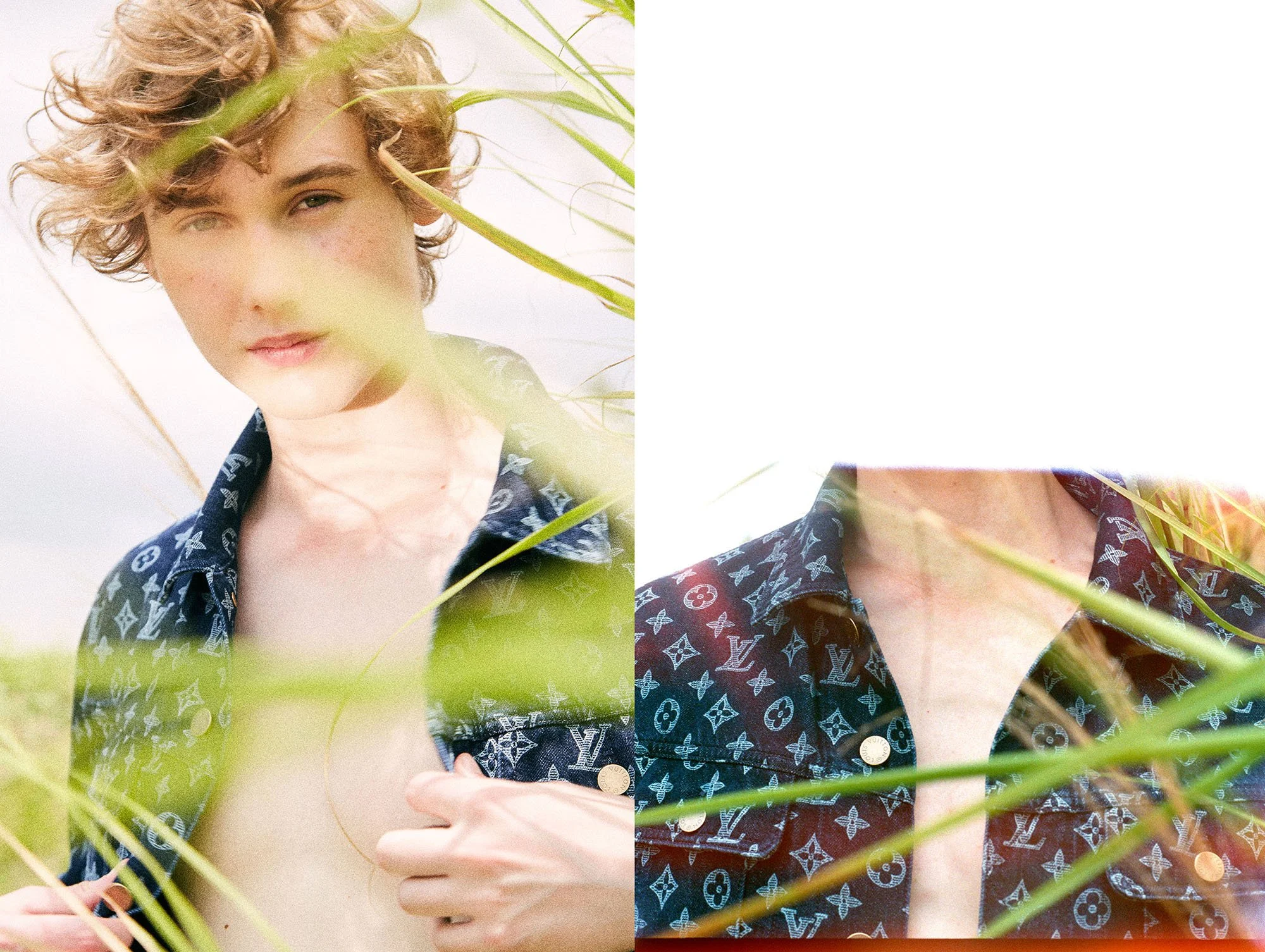 A person with curly blonde hair, wearing a dark patterned jacket, standing outdoors among green grass, partially obscured by grass blades, with a white sky background.
