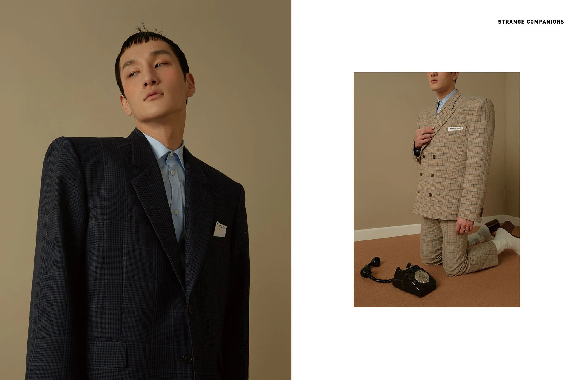 Two fashion models wearing checked suits, one standing and looking to the side with a black suit, interview scene with an old-fashioned rotary phone on the floor.