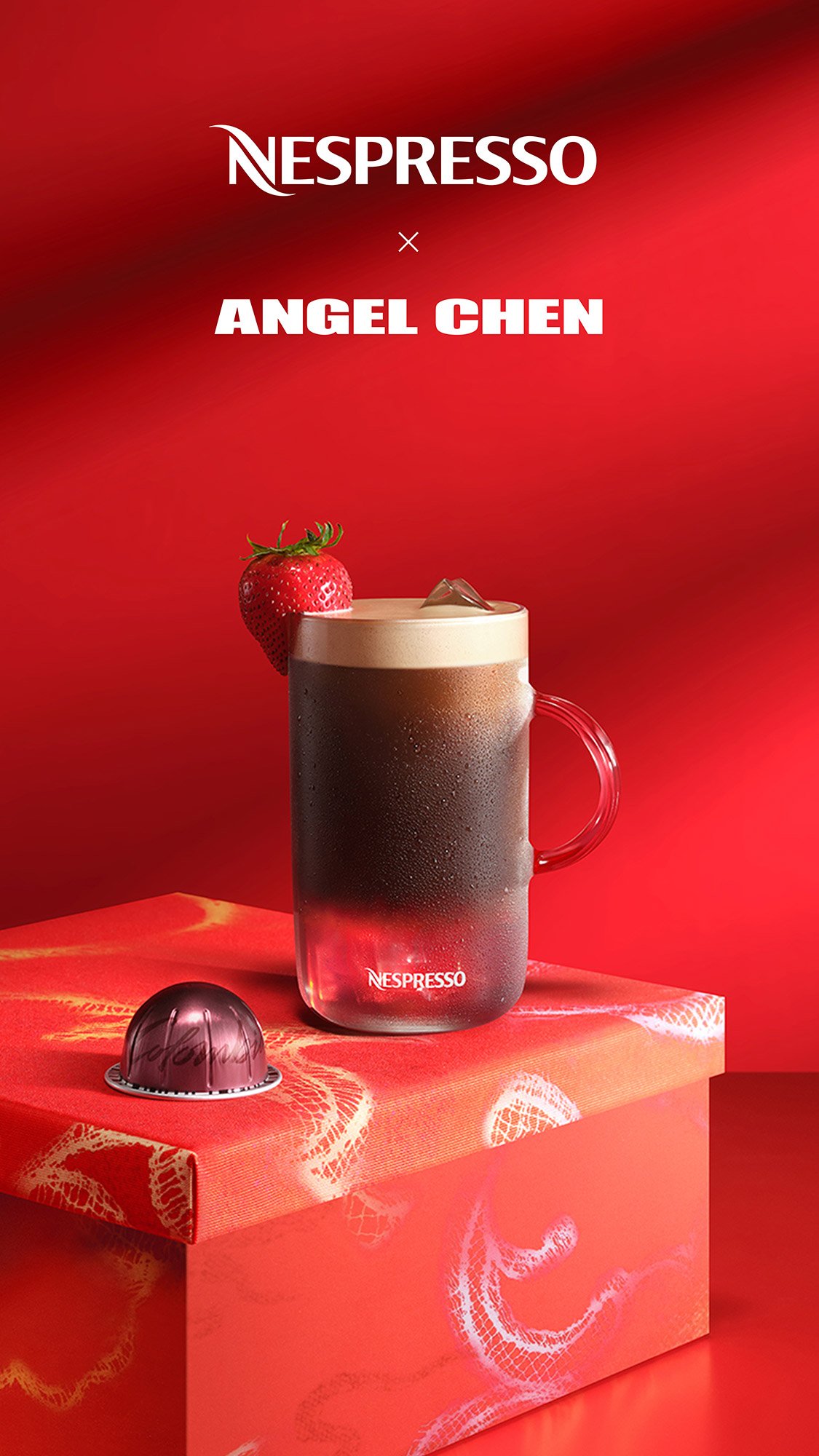 A promotional image for Nespresso featuring a glass mug of black coffee topped with whipped cream, garnished with a strawberry, and a pink Nespresso coffee capsule on a decorative orange box with a red background.
