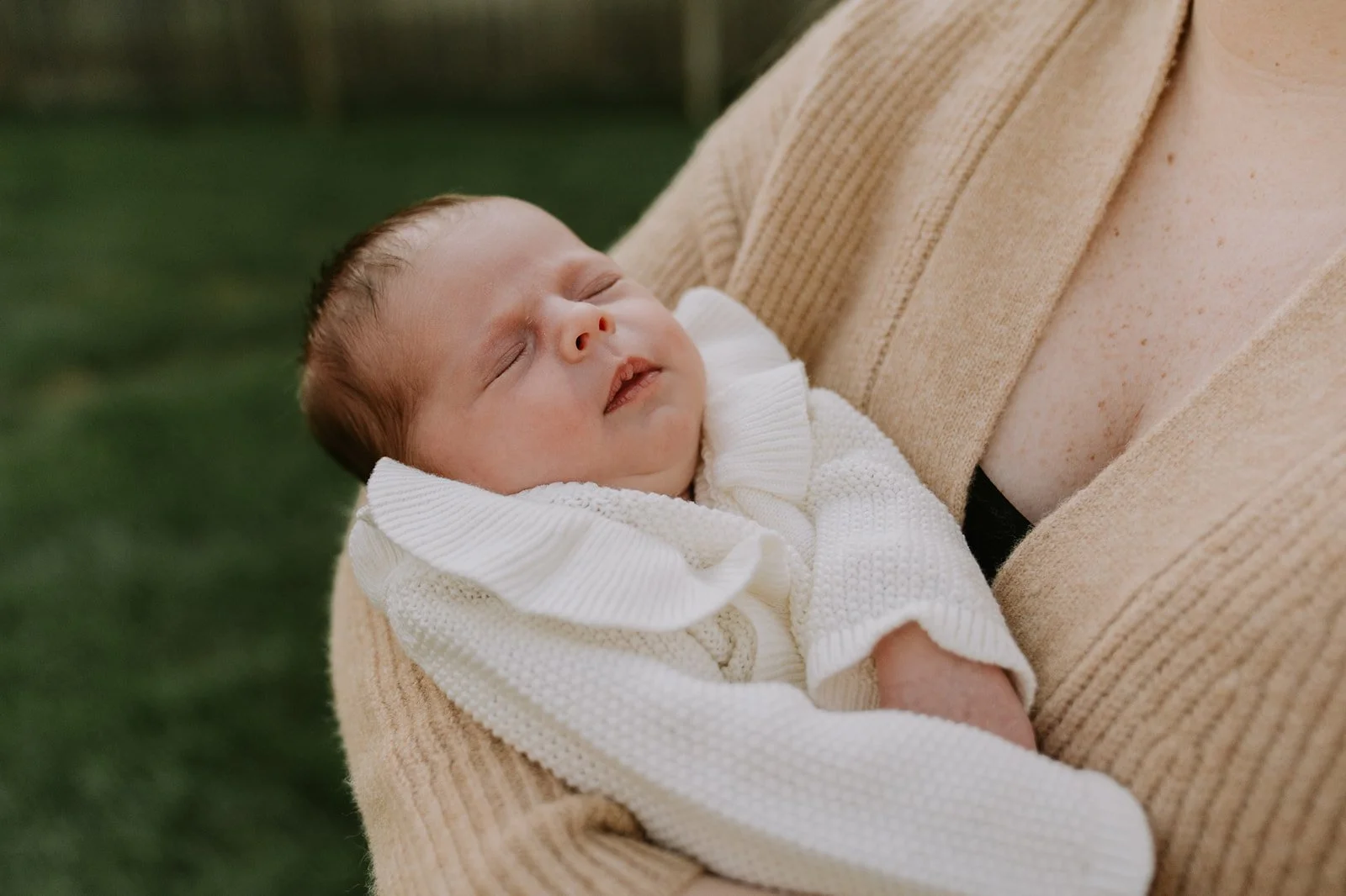 Newborn baby peacefully sleeps in their mother’s arms during an at-home newborn session in South Bend.