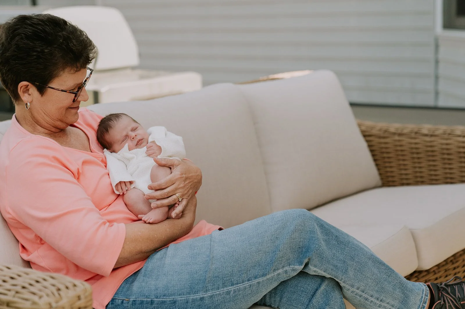 Grandmother cradles her newborn grandchild on the couch during an in-home newborn photo session in Granger, Indiana.