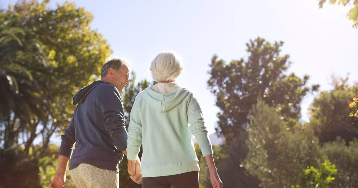 Retired couple holding hands and walking in park