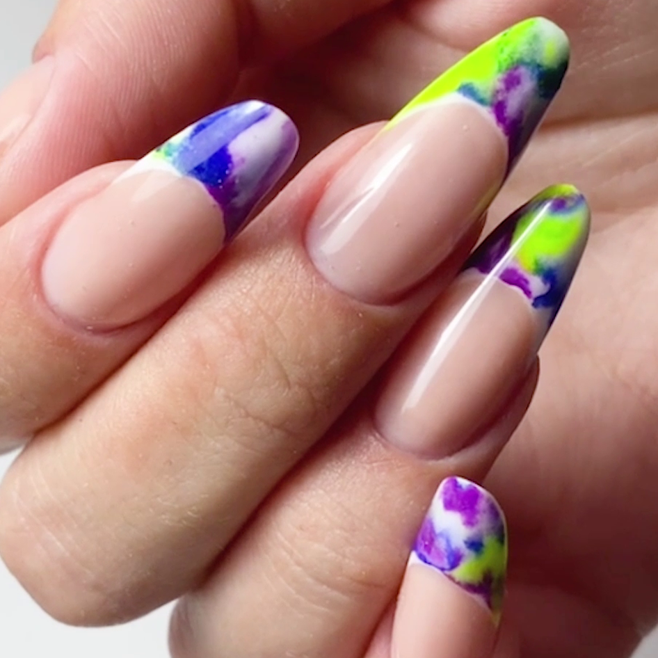 Manicure con unghie colorate di blu e verde, con effetti glitter e olografici, su una mano.