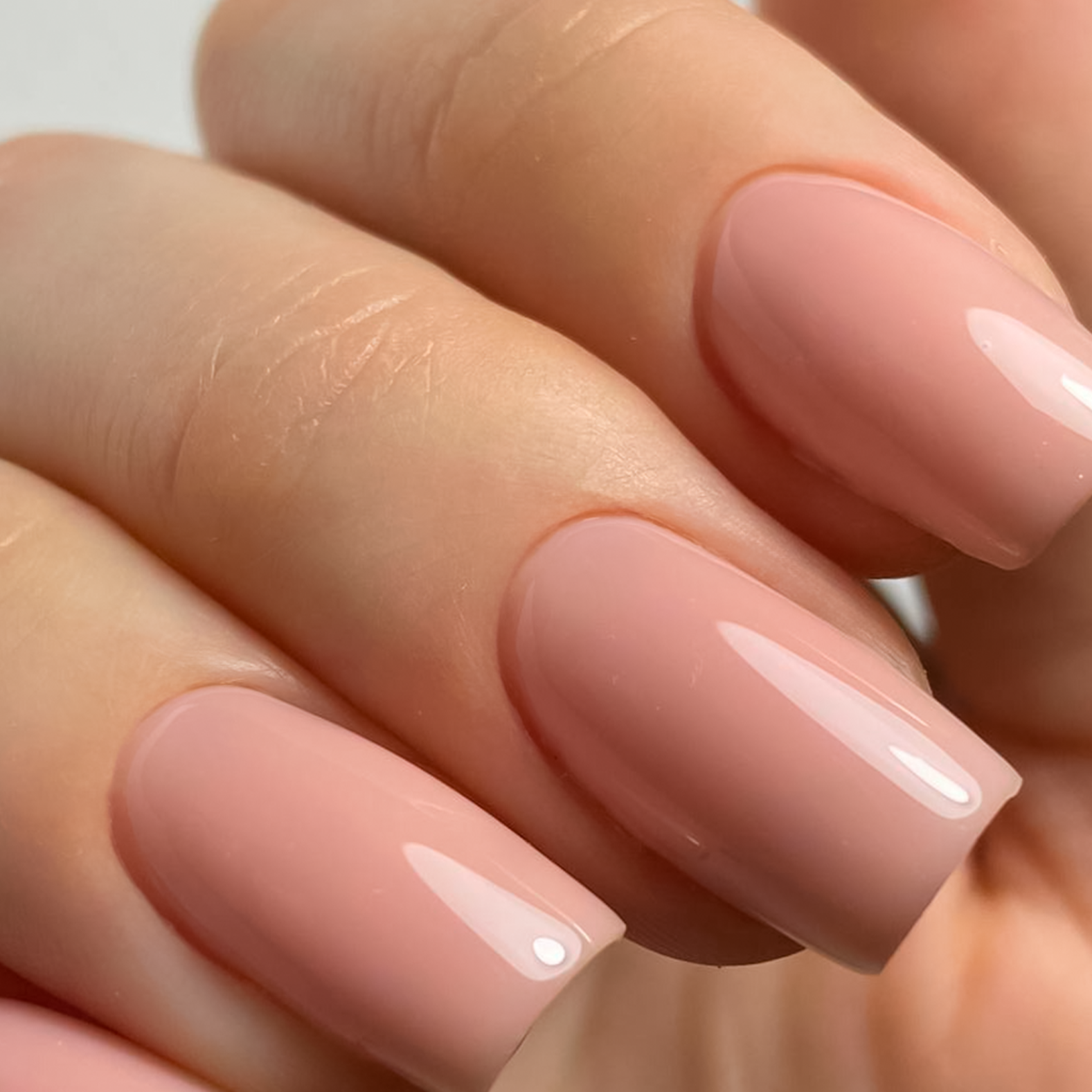 Manicure con unghie a mandorla sfumate bianco e rosa, su una mano femminile.