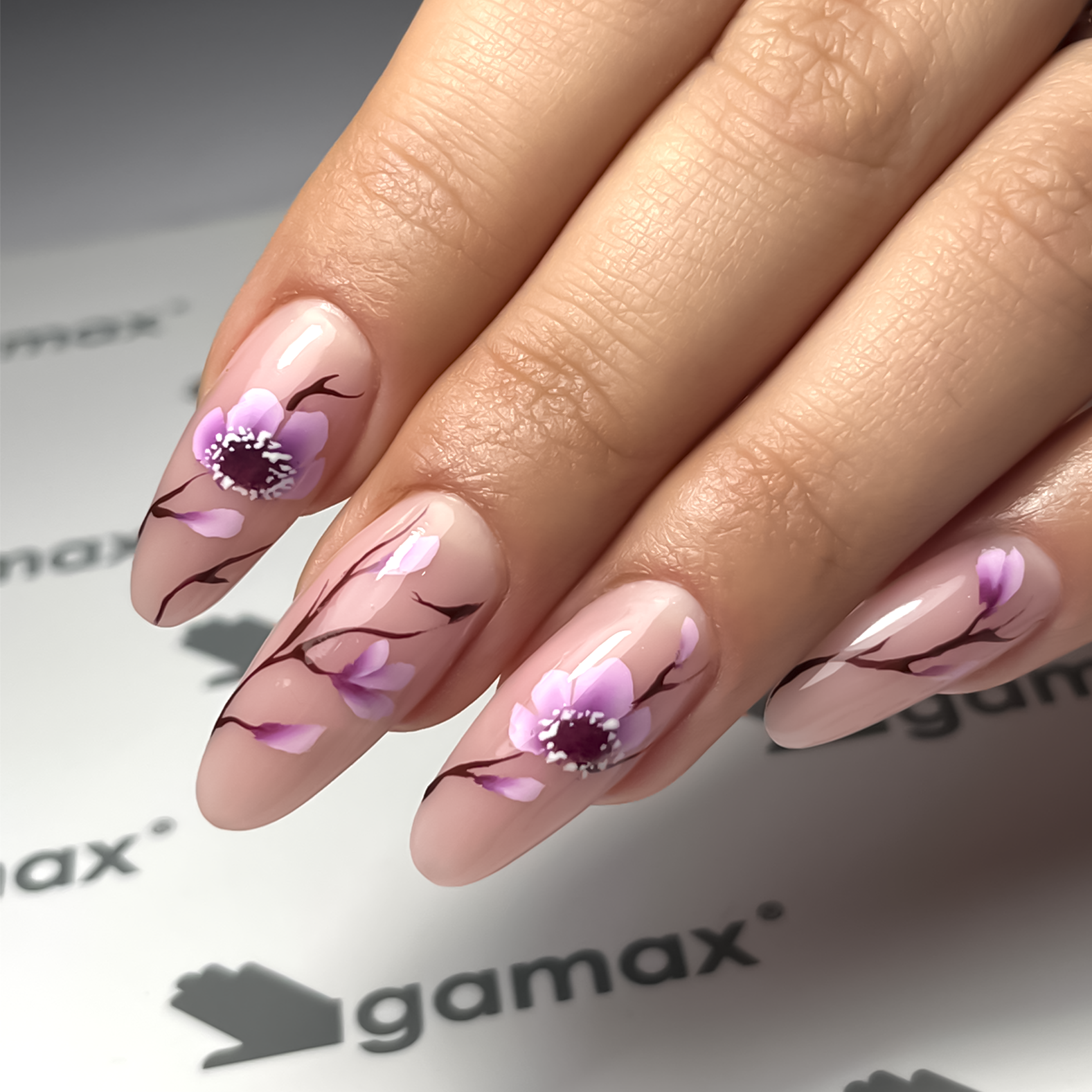 Mano con unghie decorate con nail art su sfondo beige.