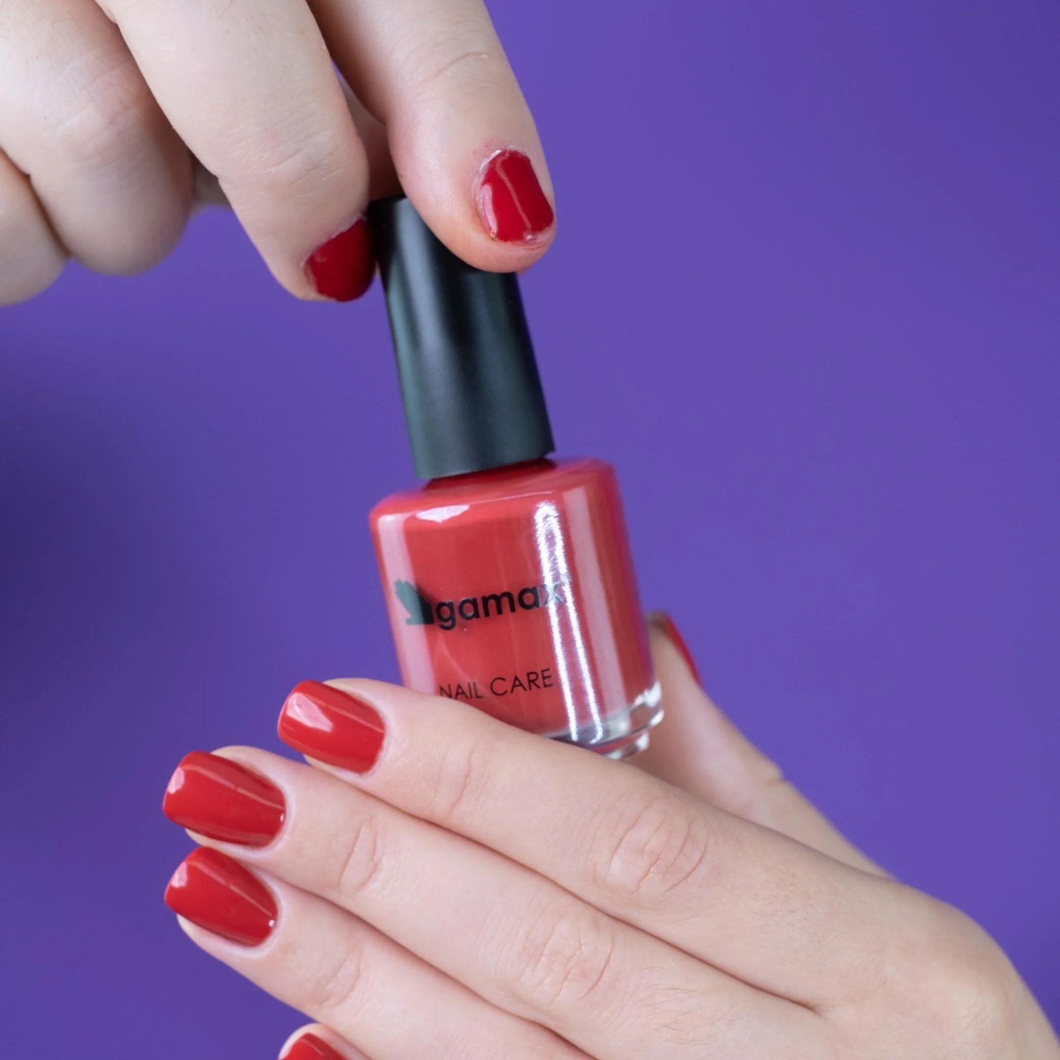 Dettaglio mano tenendo un smalto rosso gamax